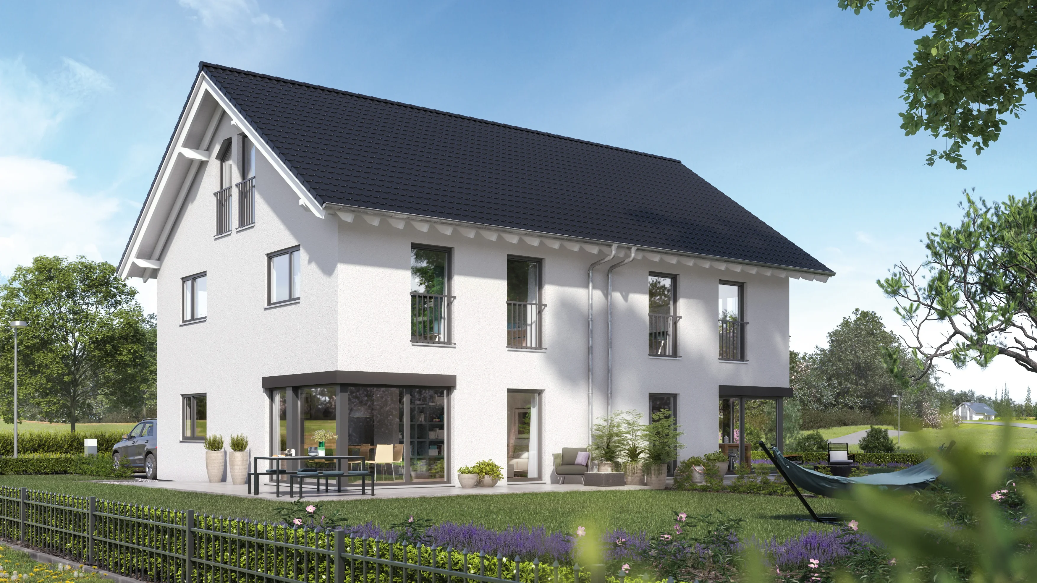 Modernes weißes Einfamilienhaus mit dunklem Dach, umliegendem Garten mit Zaun, Hängematte und Außensitzgruppe.