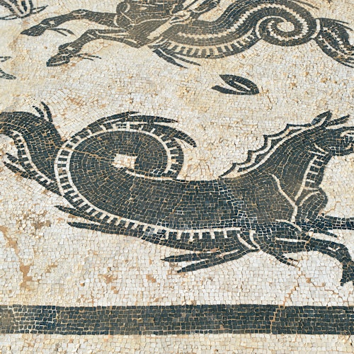 Ancient mosaic featuring a black, stylized horse and serpent-like creatures against a white and beige background.