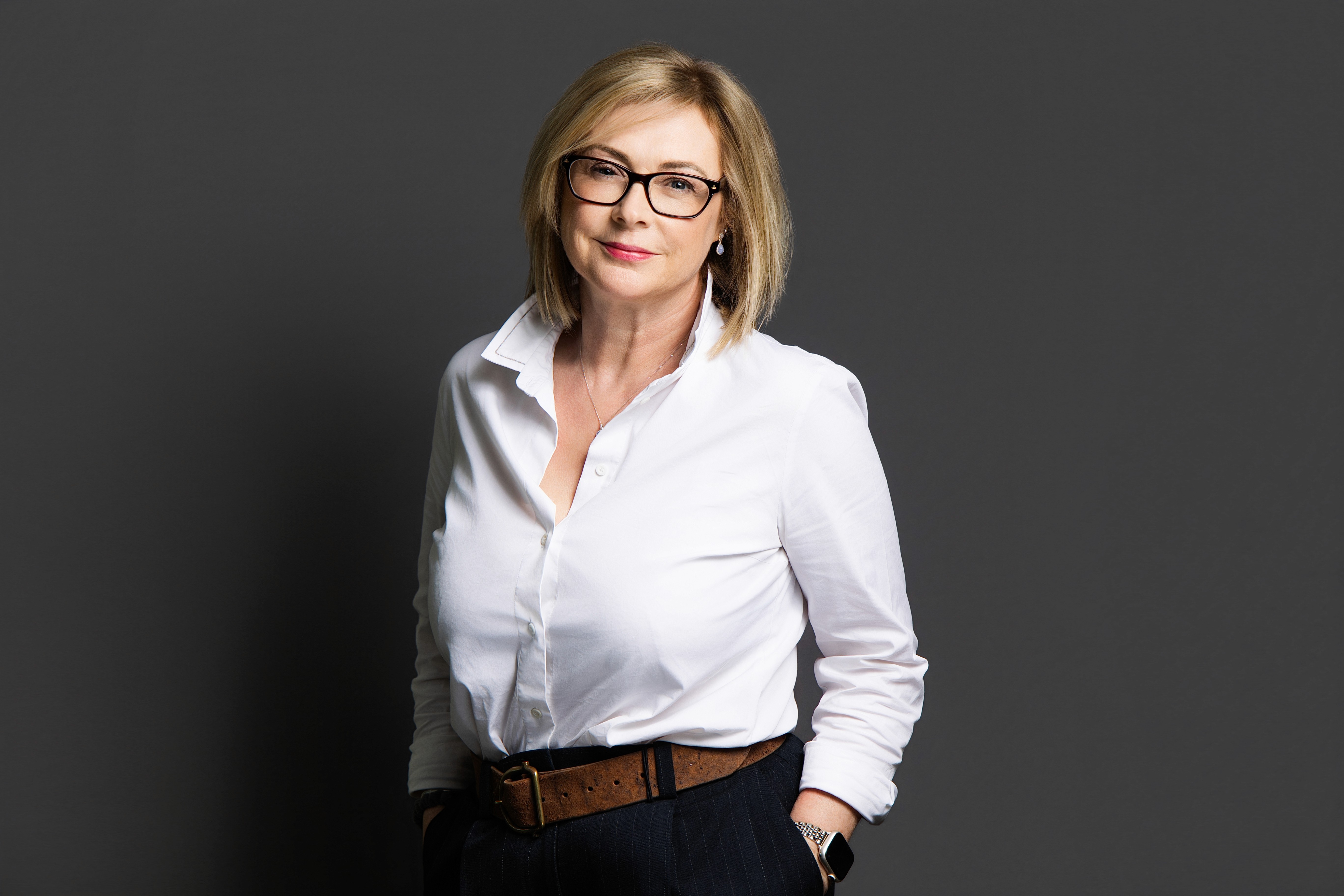 A man with glasses and a brown shirt, crossing his arms.