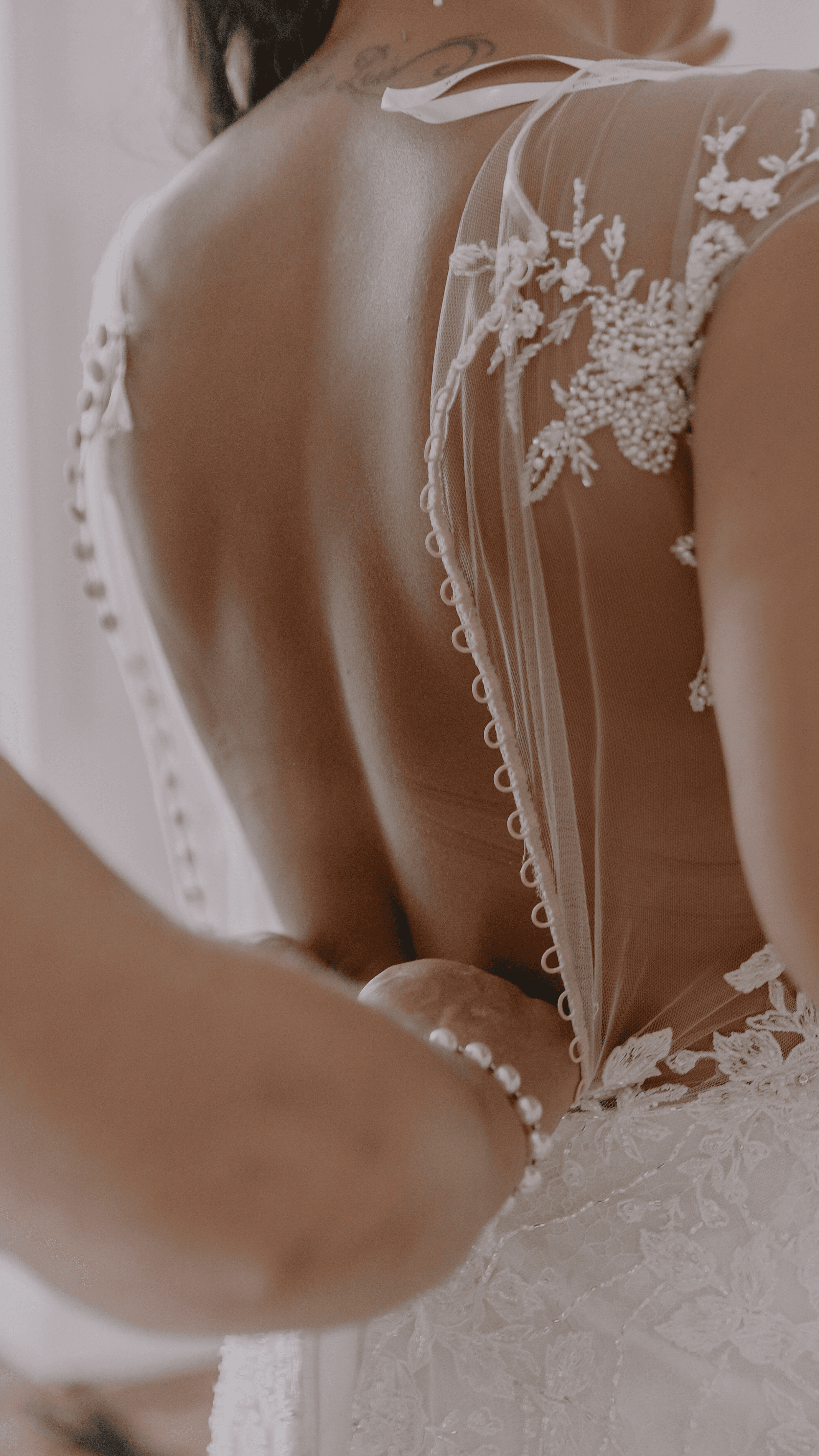 Back view of a bride being fitted in to her wedding dress