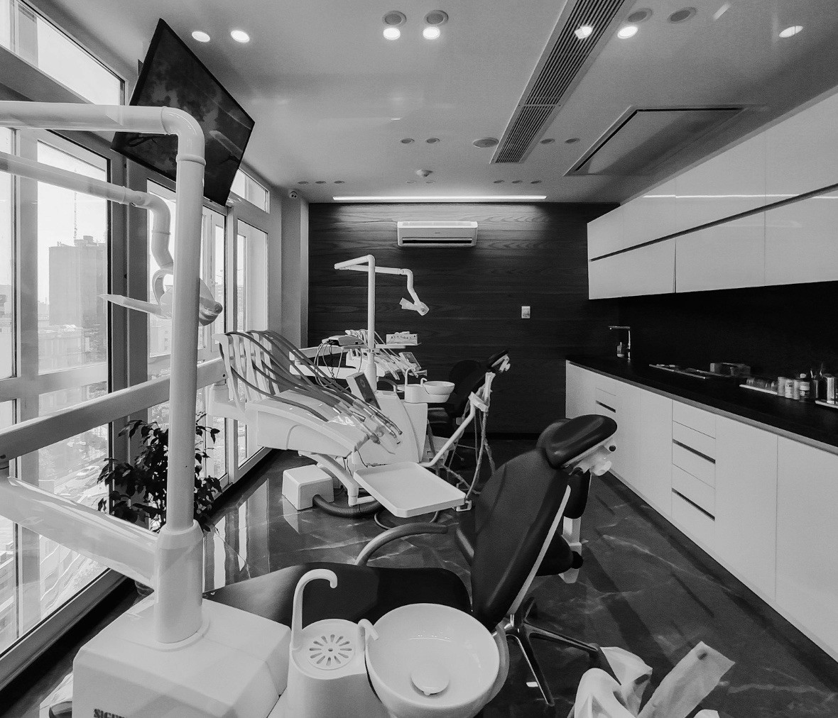Black and white photo of a surgeon in a mask, cap, and magnifying loupes, looking down with intense focus