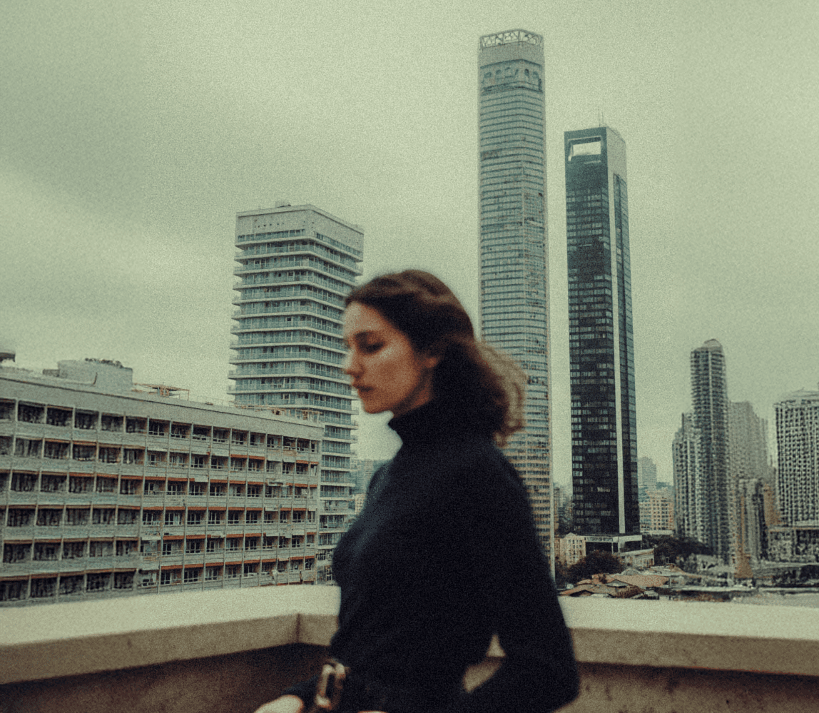 blurry women standing on a rooftop in from of a city witha cloudy sky