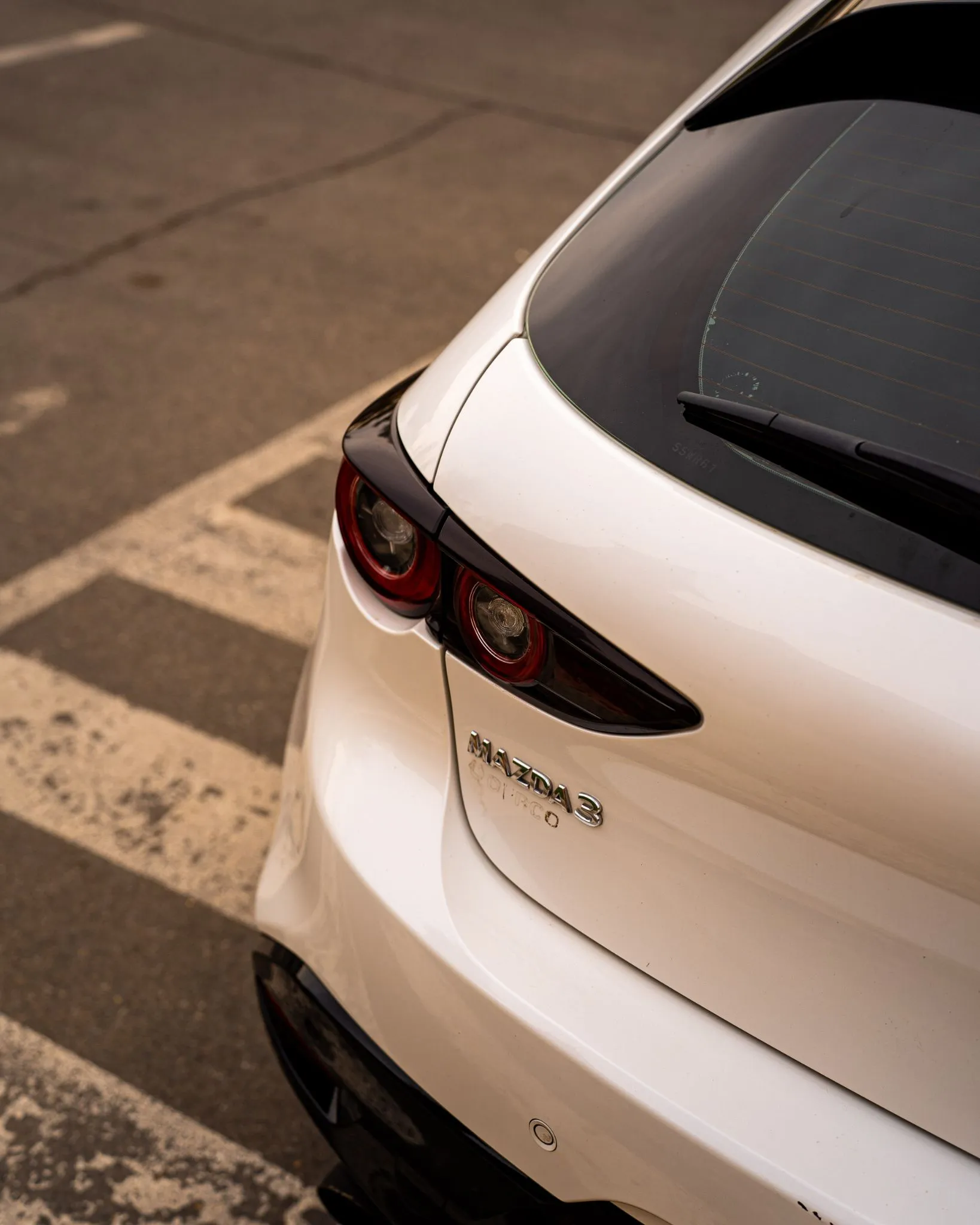 Detalle trasero del Mazda 3 blanco con focos circulares y emblema Skyactiv-G