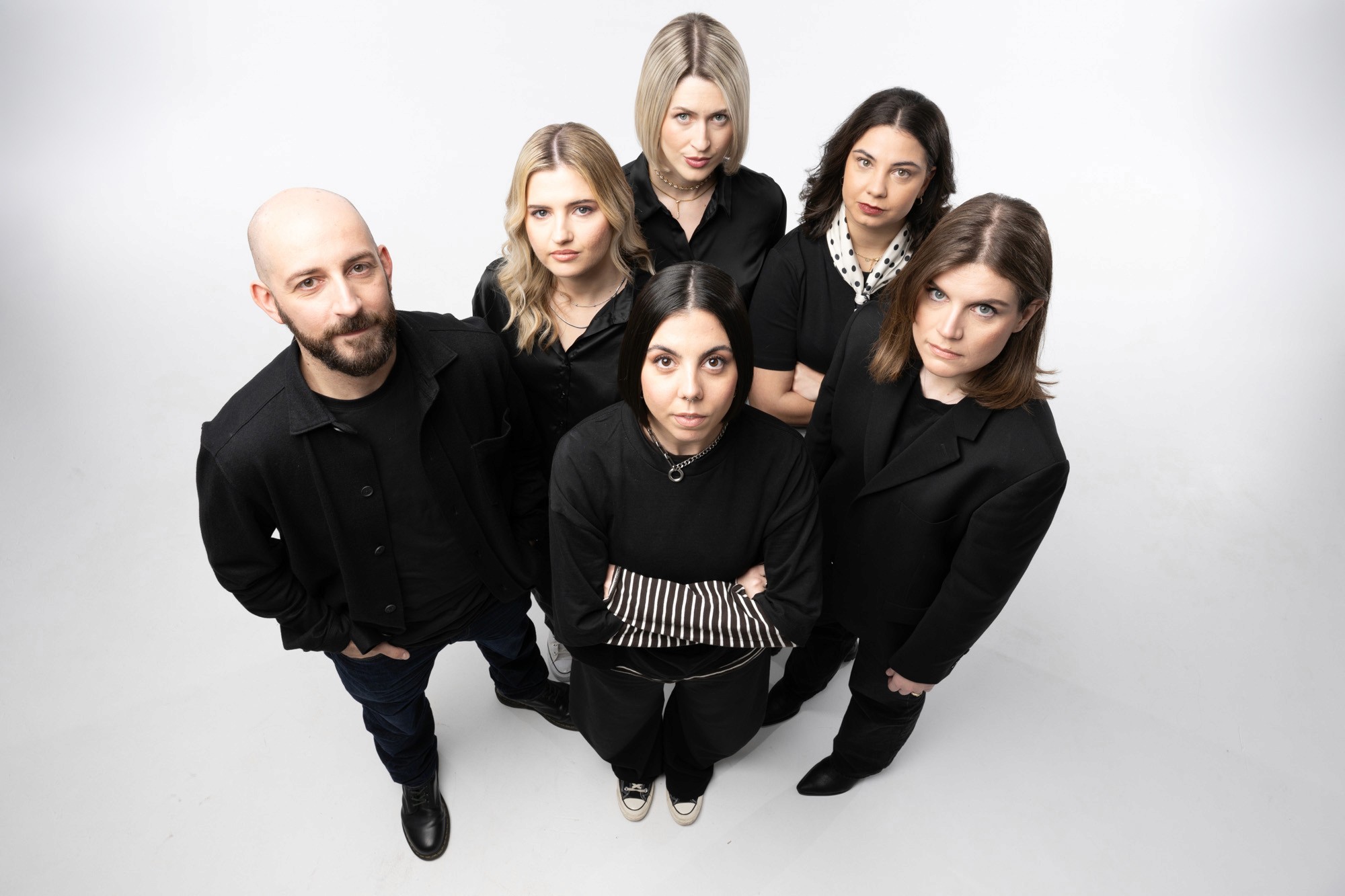 Black and white image of people working at a table with laptops, showing hands gesturing during discussion of digital content displayed on screens, with fabrica® logo in the corner.