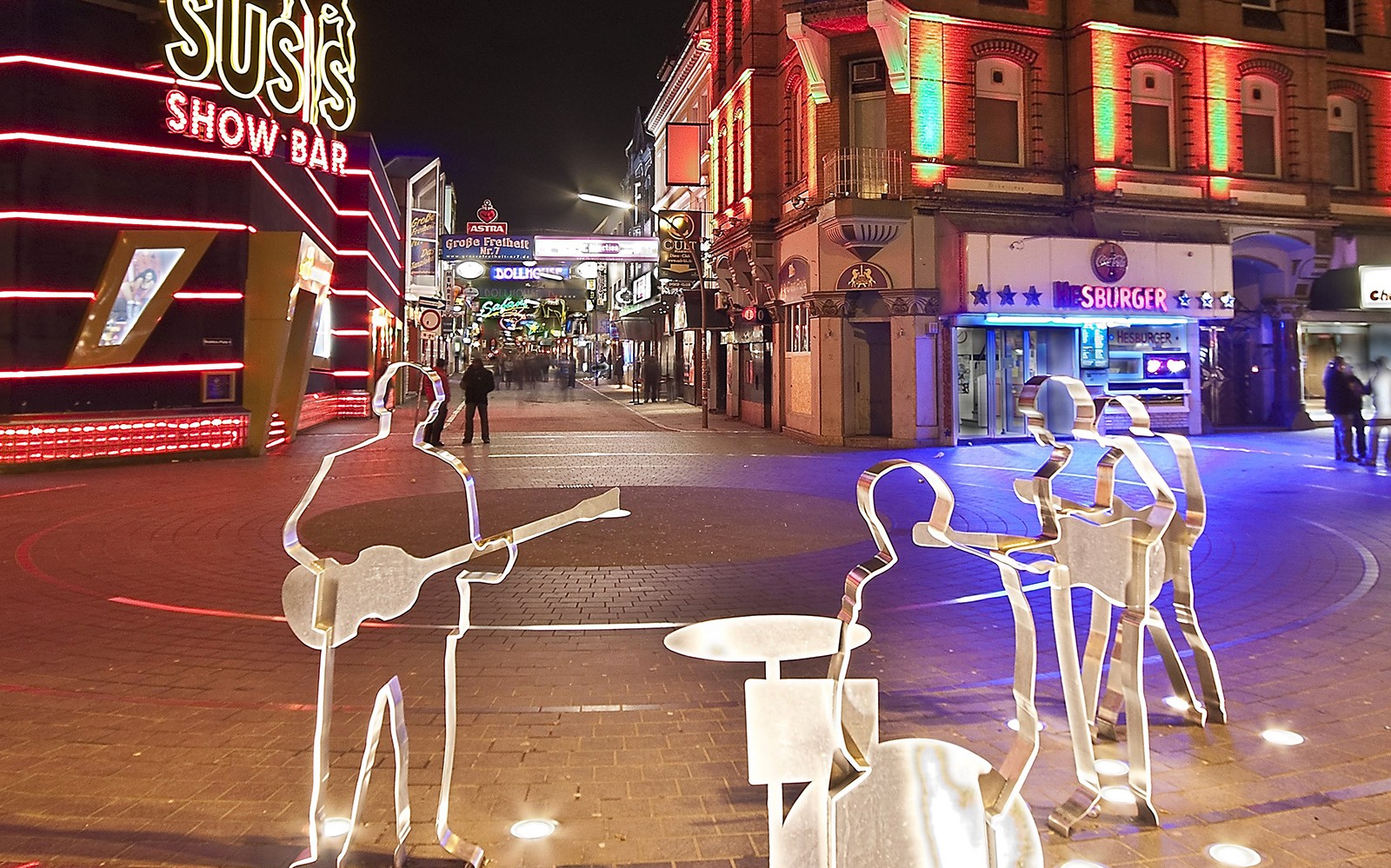 St. Pauli nightlife scene with illuminated bars and metal sculptures, Hamburg.