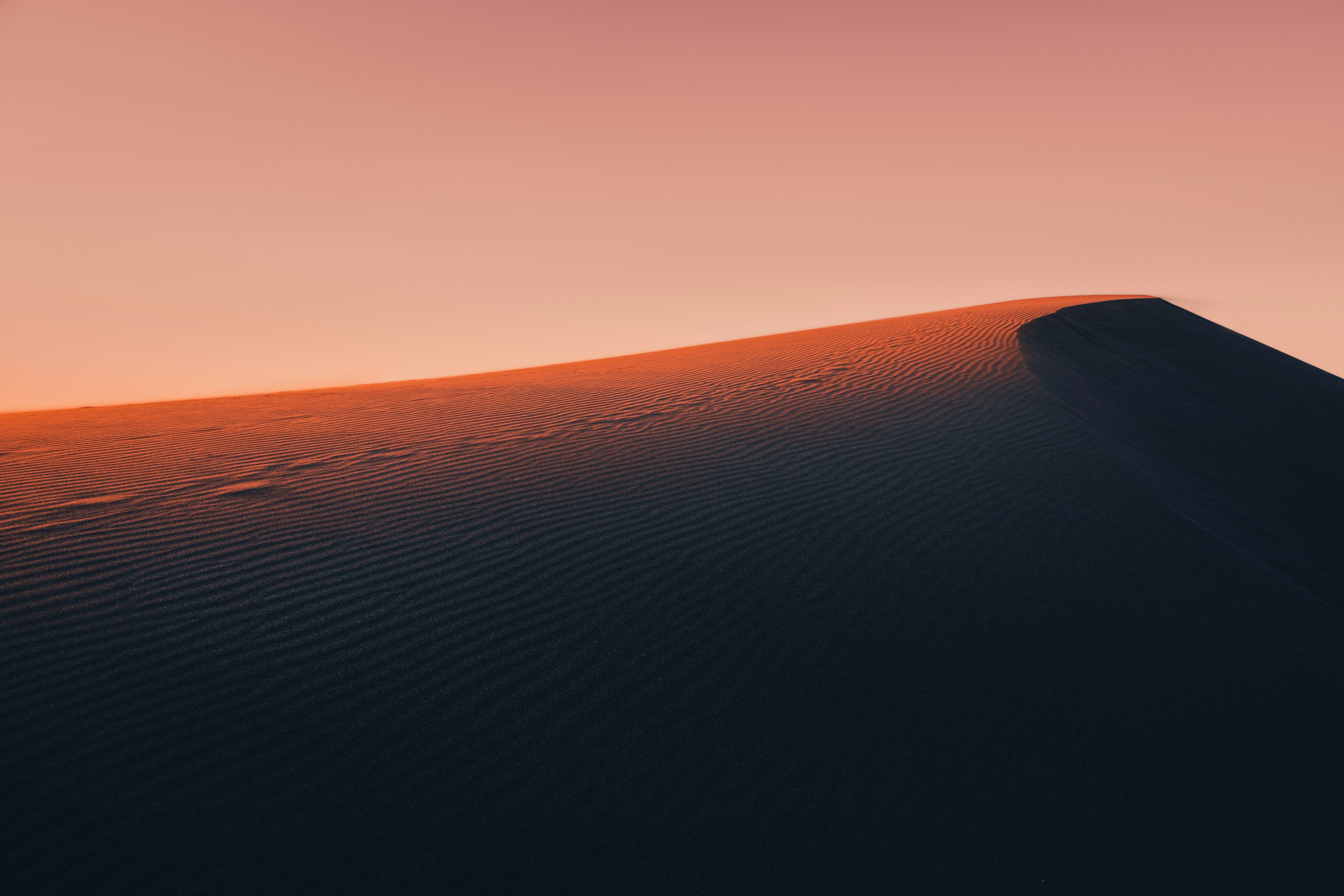 A photo of a desert sand dune at sunrise.