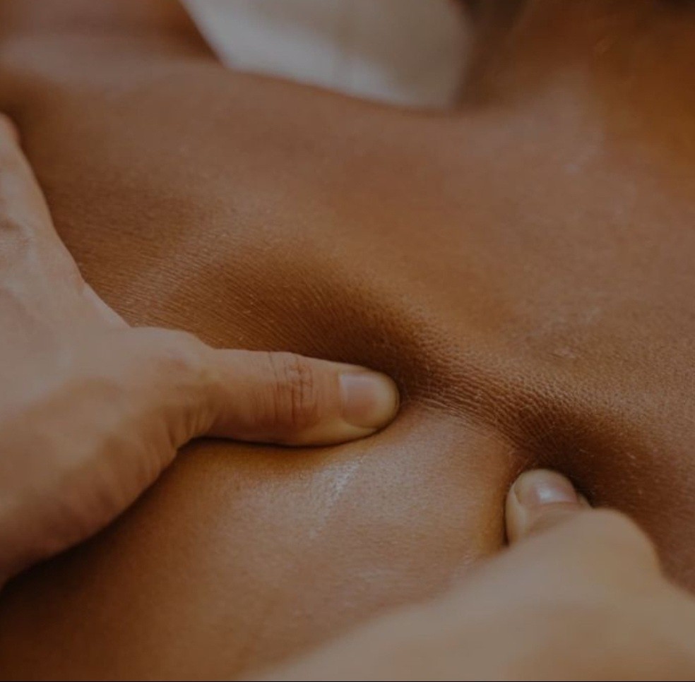A close-up of hands performing a relaxing massage, with warm golden light illuminating the skin. The scene evokes a sense of relaxation and well-being.