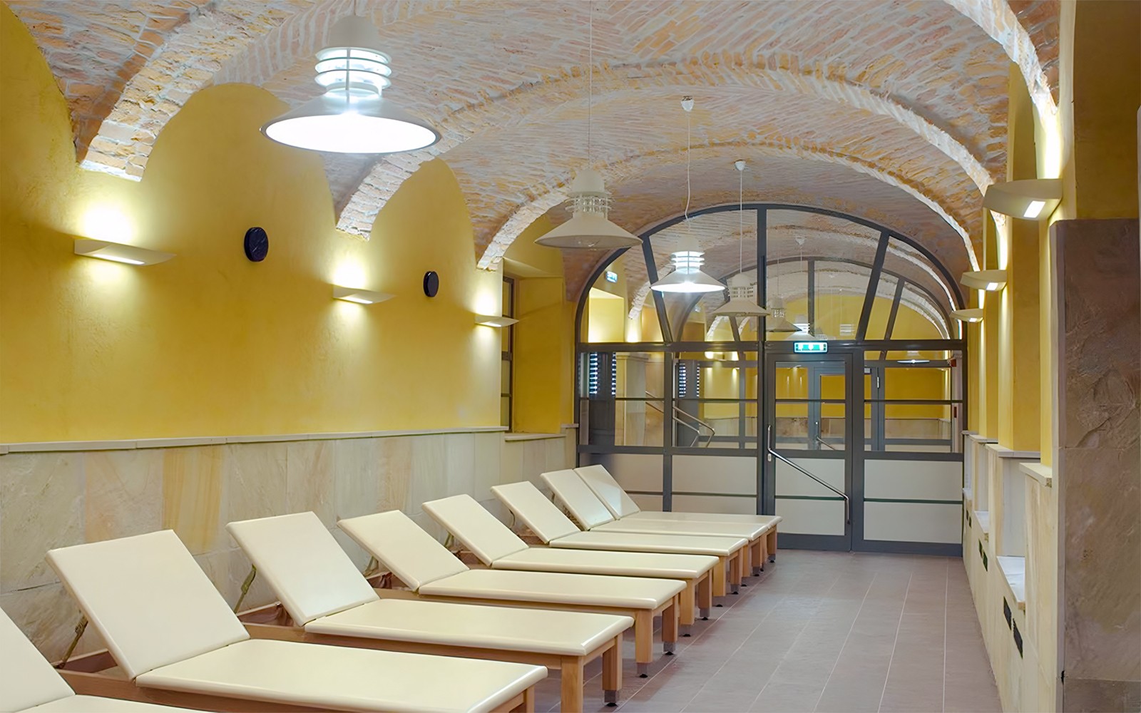 Loungers inside Rudas Thermal Spa with arched brick ceiling and warm lighting.