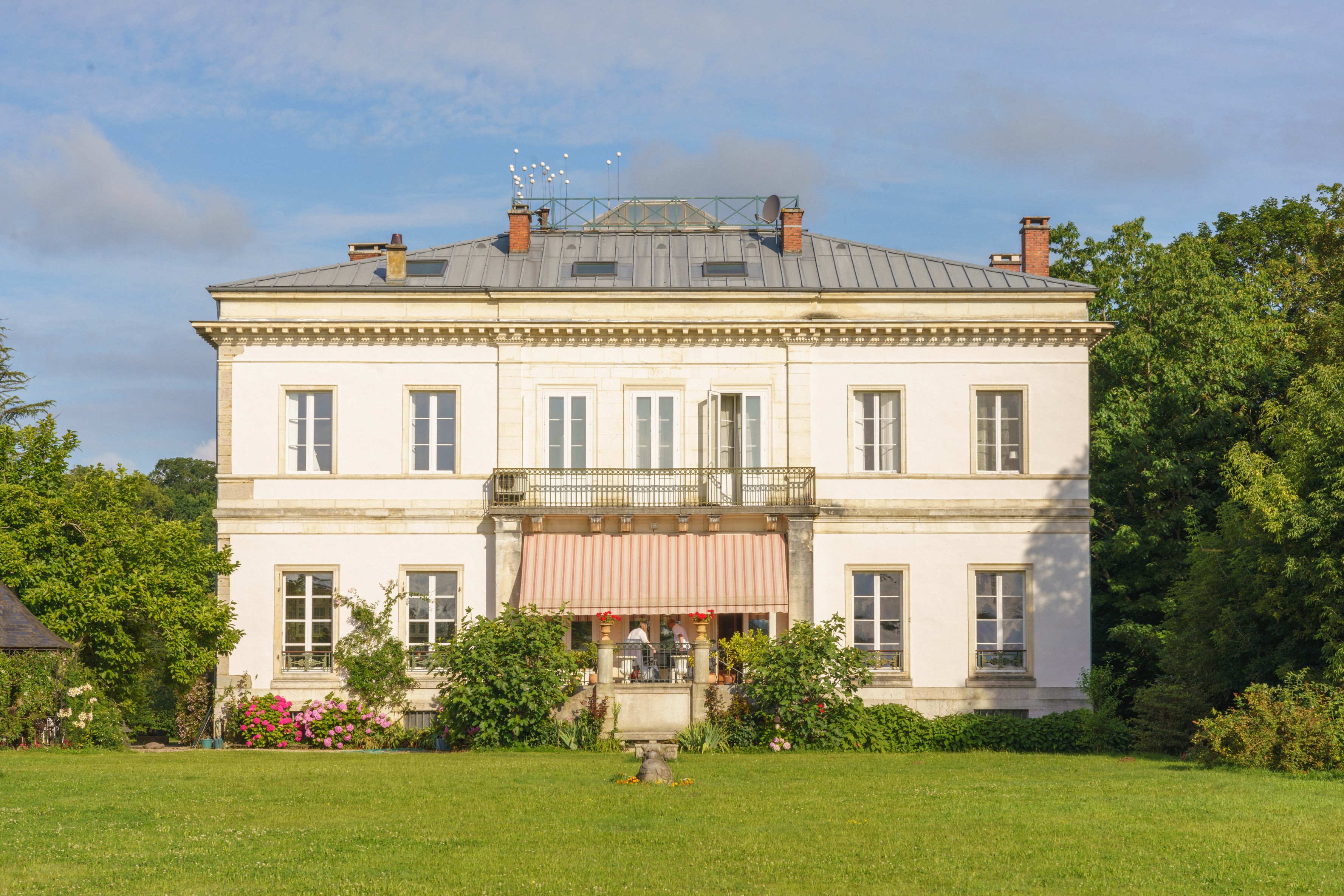 White period villa with awnings set in landscaped grounds