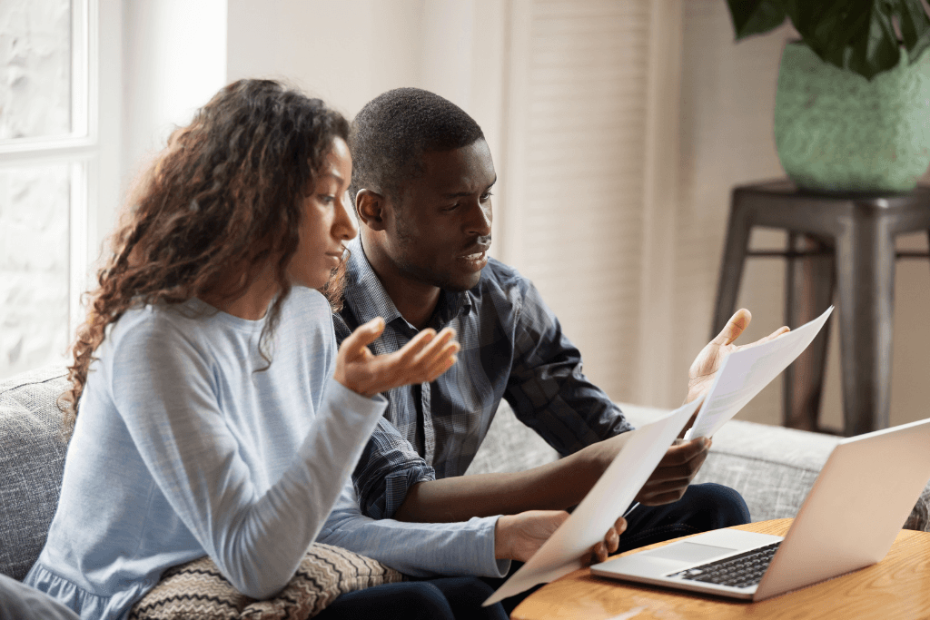 Concerned black couple read bills considering paperwork at home