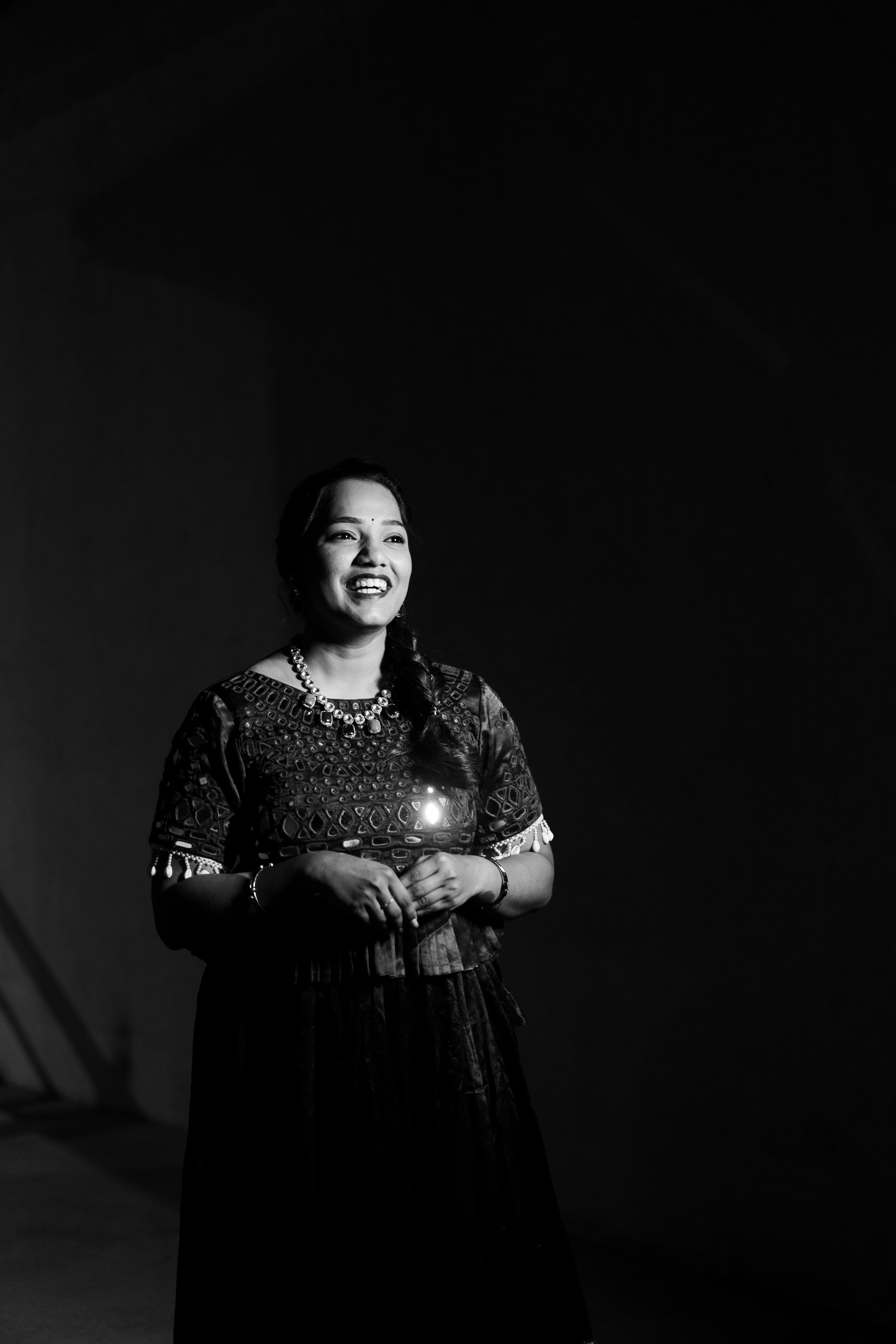 In a black and white image, Vishwani gracefully holds a candle, radiating warmth and elegance. Photo by Out of The Blues Fine Art Wedding Photography in Hyderabad.