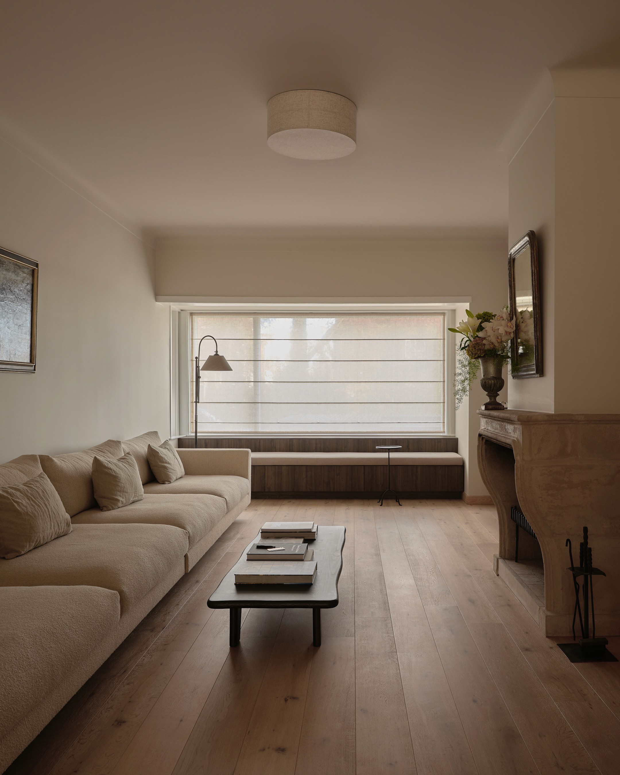 Living space with sofa, coffee table with books, fireplace, bespoke window seat and curated artwork collection