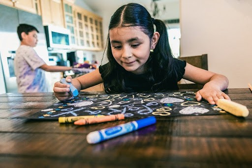 Girl writes with chalks on the table