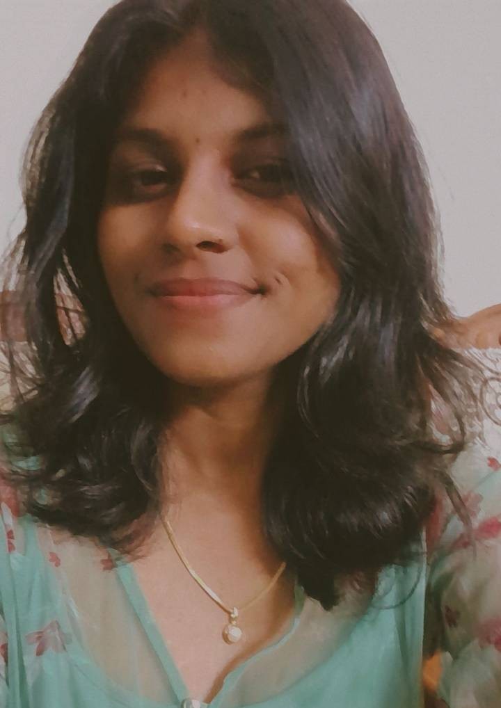 a man wearing glasses and a blazer with a lighting that casts a soft shadow on the wall behind him