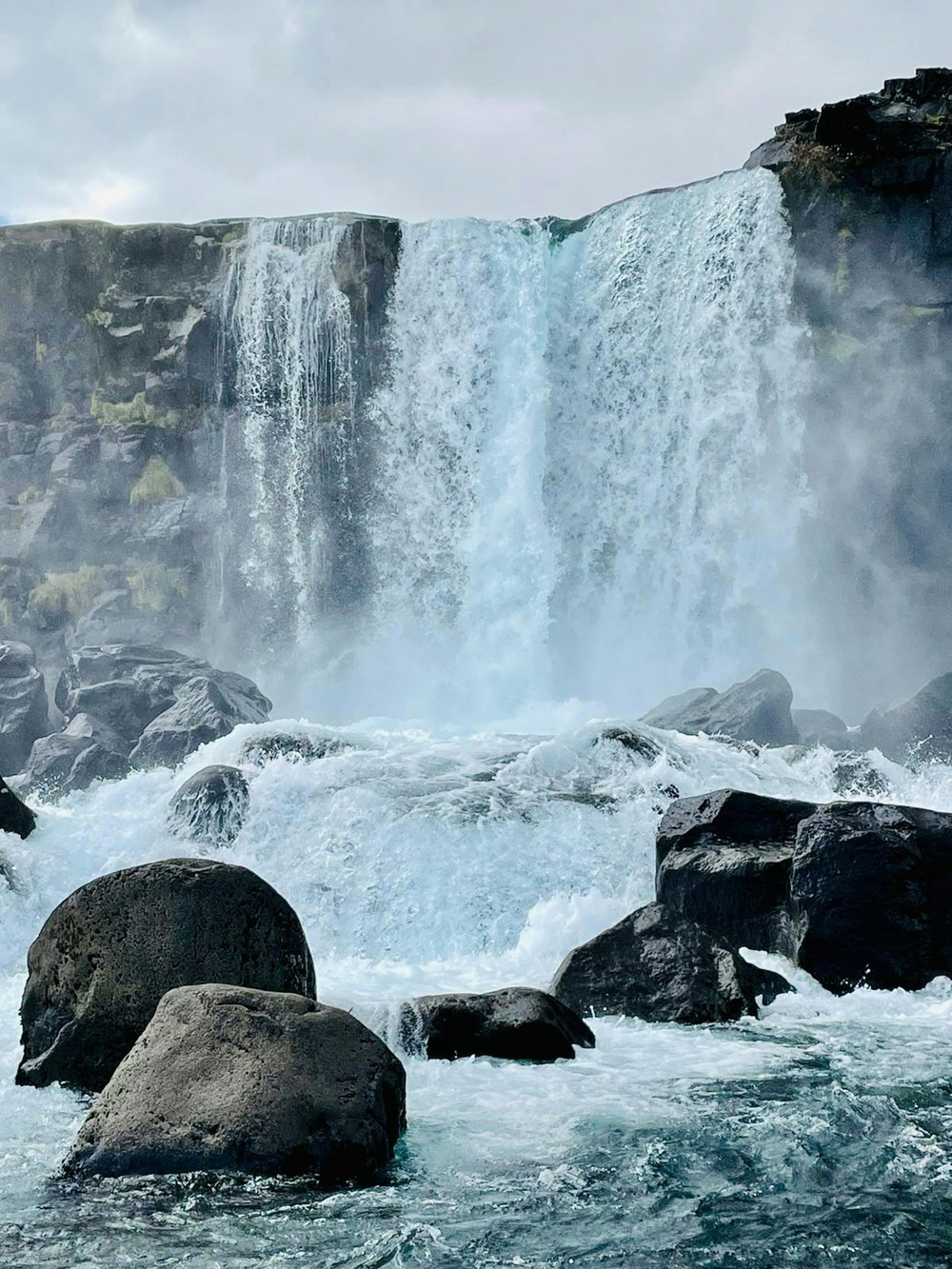Powerful waterfall cascading over dark volcanic rocks near Reykjavik, Iceland