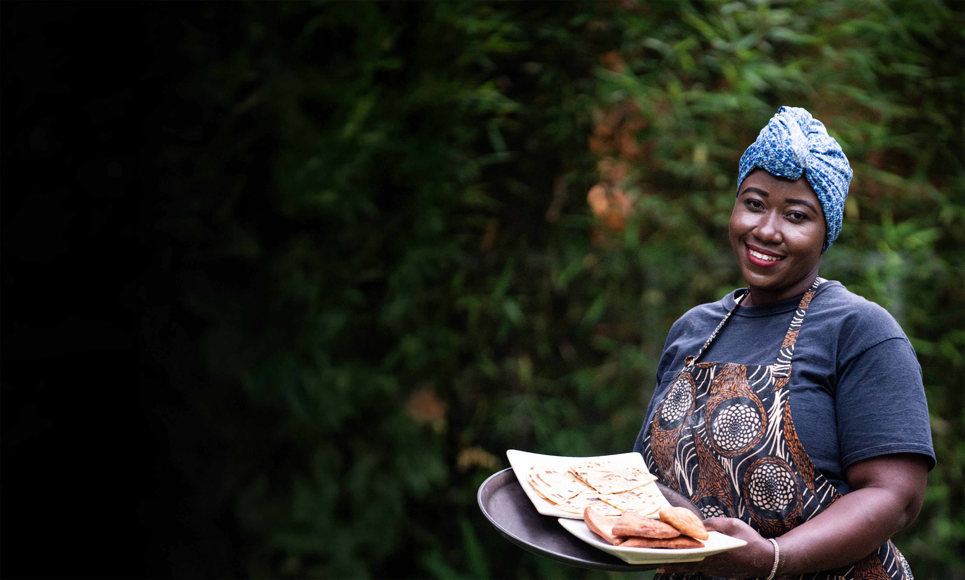 Woman holding a tray of chapati and mandazi made with Essential's protein
