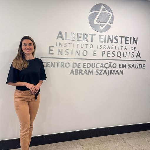 Bruna Pagotto, especialista em Neurociências, em frente ao Instituto Israelita Albert Einstein, destacando sua participação no Centro de Educação em Saúde Abram Szajman. Sua expertise em neurodesenvolvimento infantil e sua atuação em pesquisa contribuem para avanços no cuidado e aprendizado na área da saúde infantil.