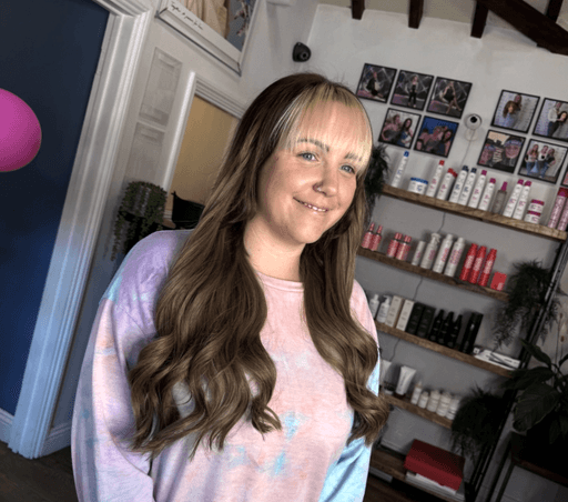 Smiling woman with long wavy brunette hair and blonde fringe