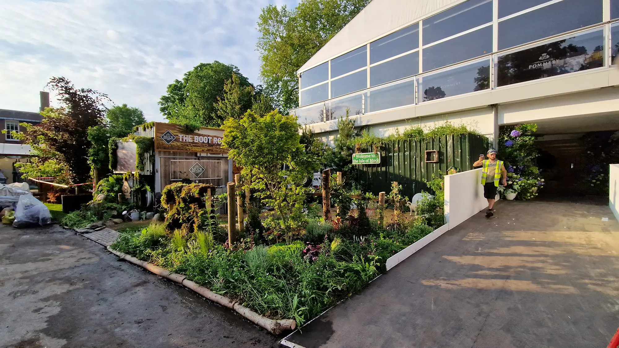 A well-kept garden with flowers and greenery beside a modern building entrance and paved pathway.