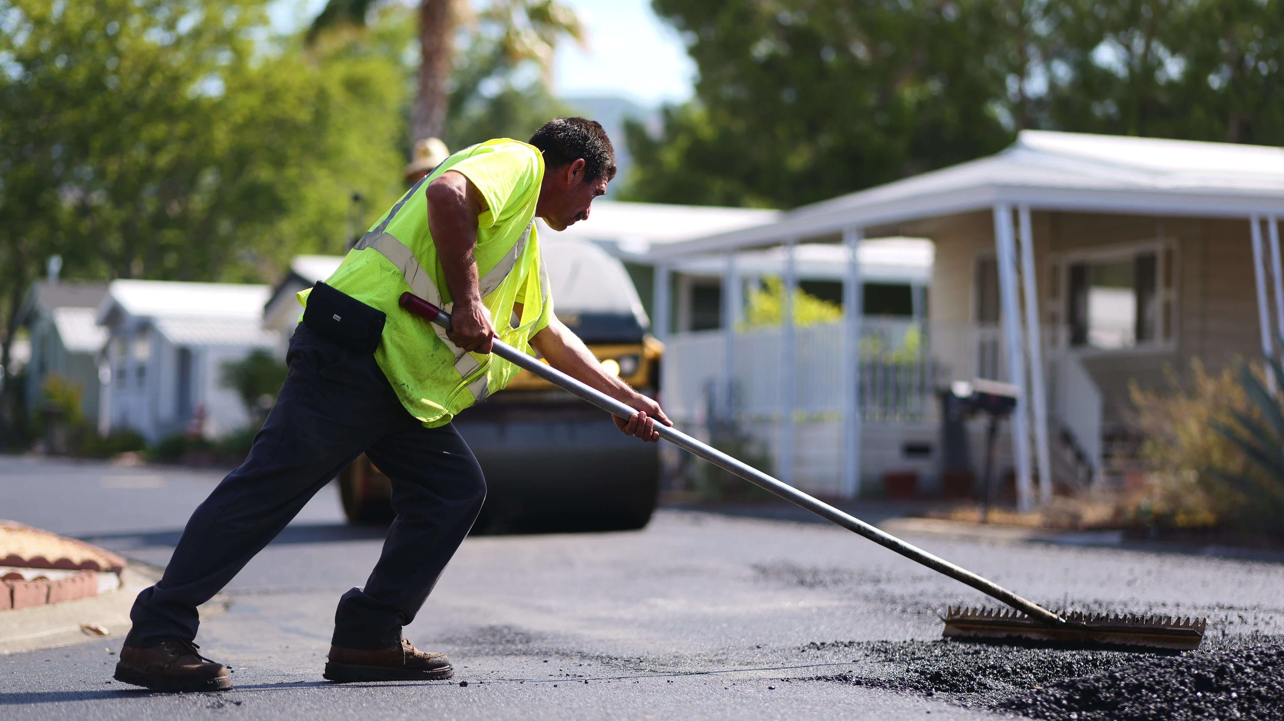 Asphalt crew raker leveling a skin patch on project