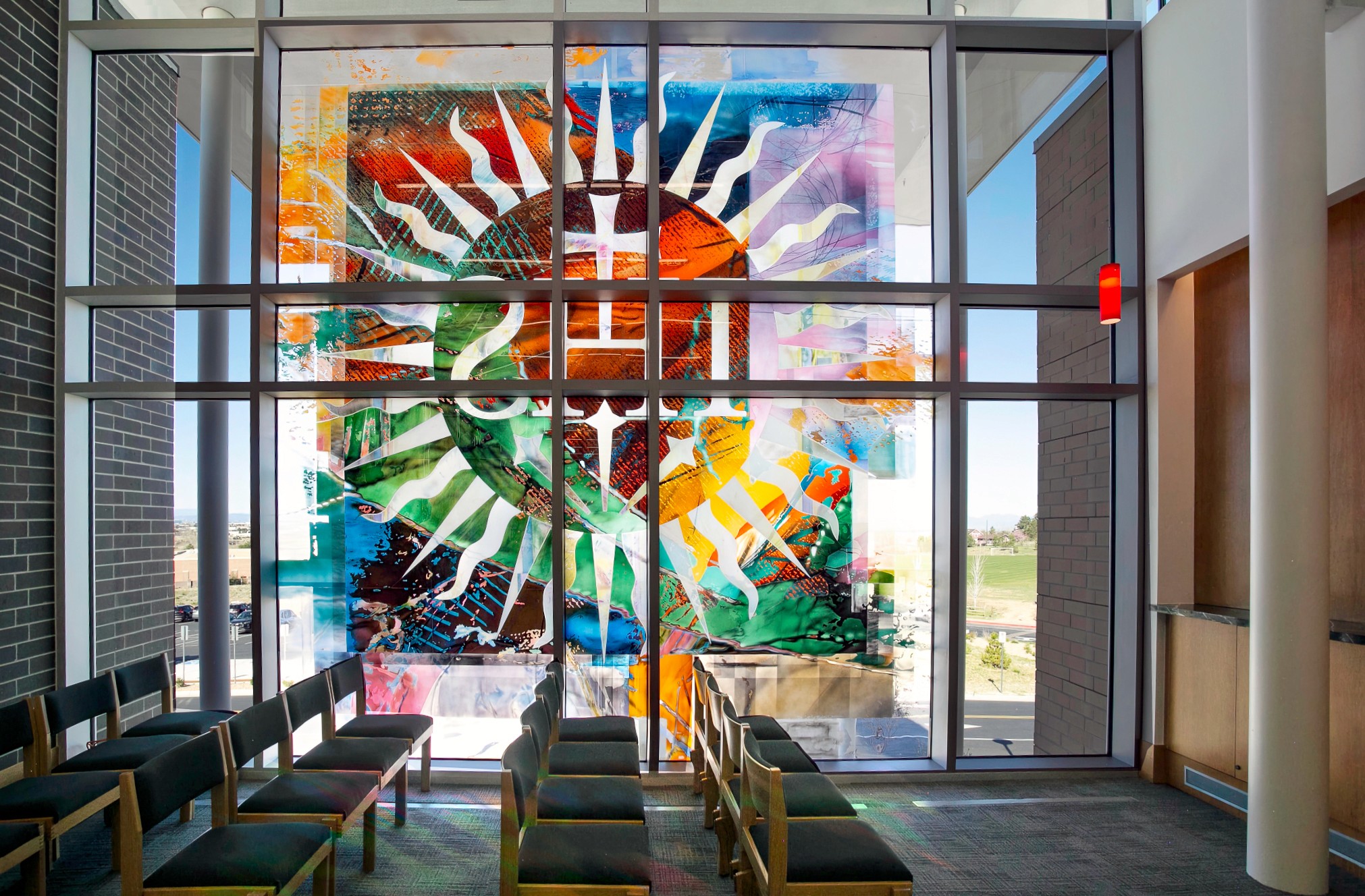 Liturgical stained glass transforming chapel interior with natural light, custom commission for Jesuit worship space