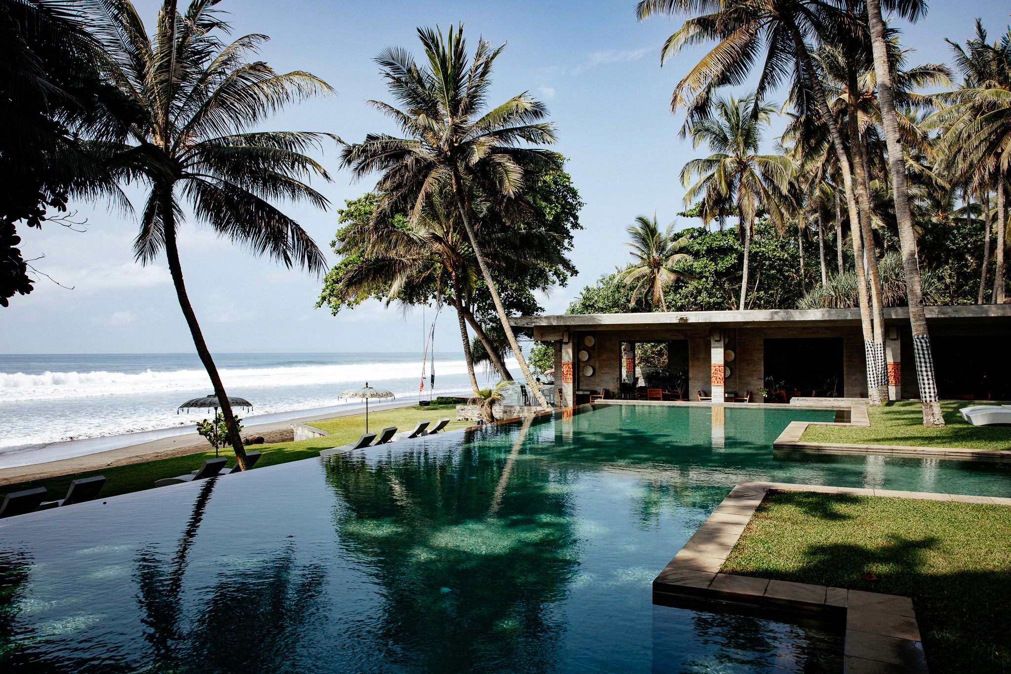 Infinity-Pool mit Palmenblick und direktem Zugang zum Strand – Exklusive Hotelfotografie aus dem Kelapa Retreat & Spa Resort, Bali