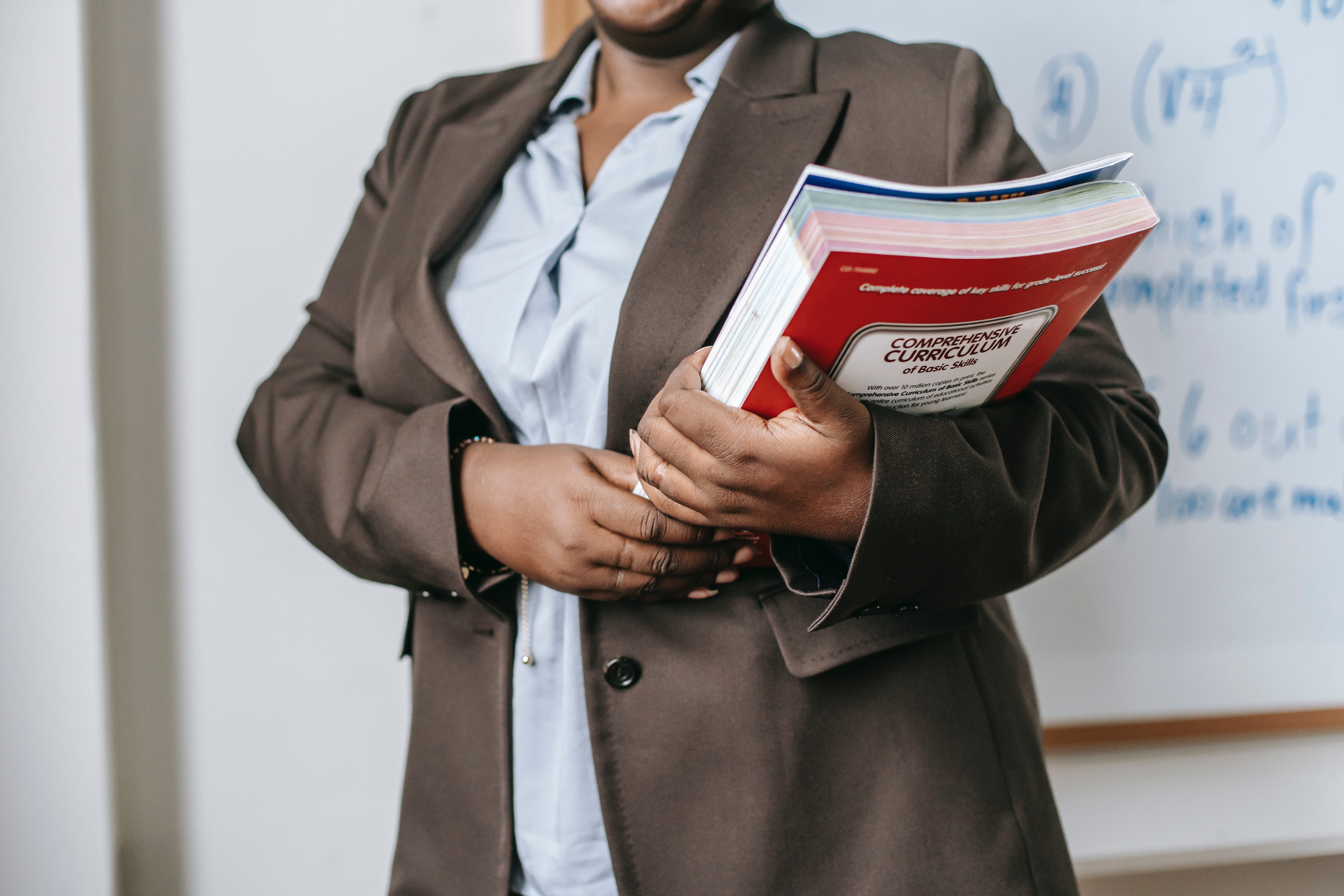 Woman in a classroom holding a set of books