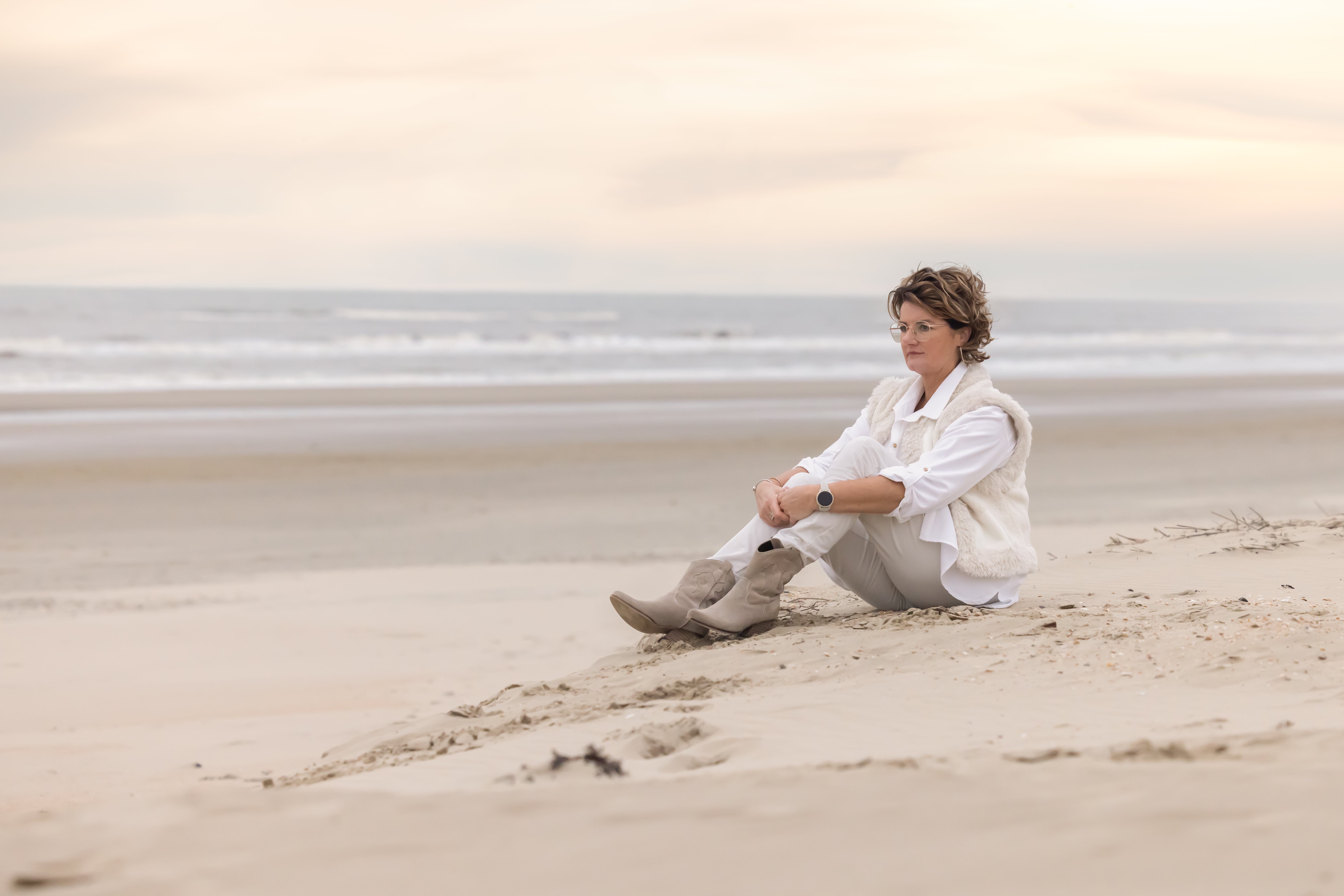 petra zittend in het zand op het strand