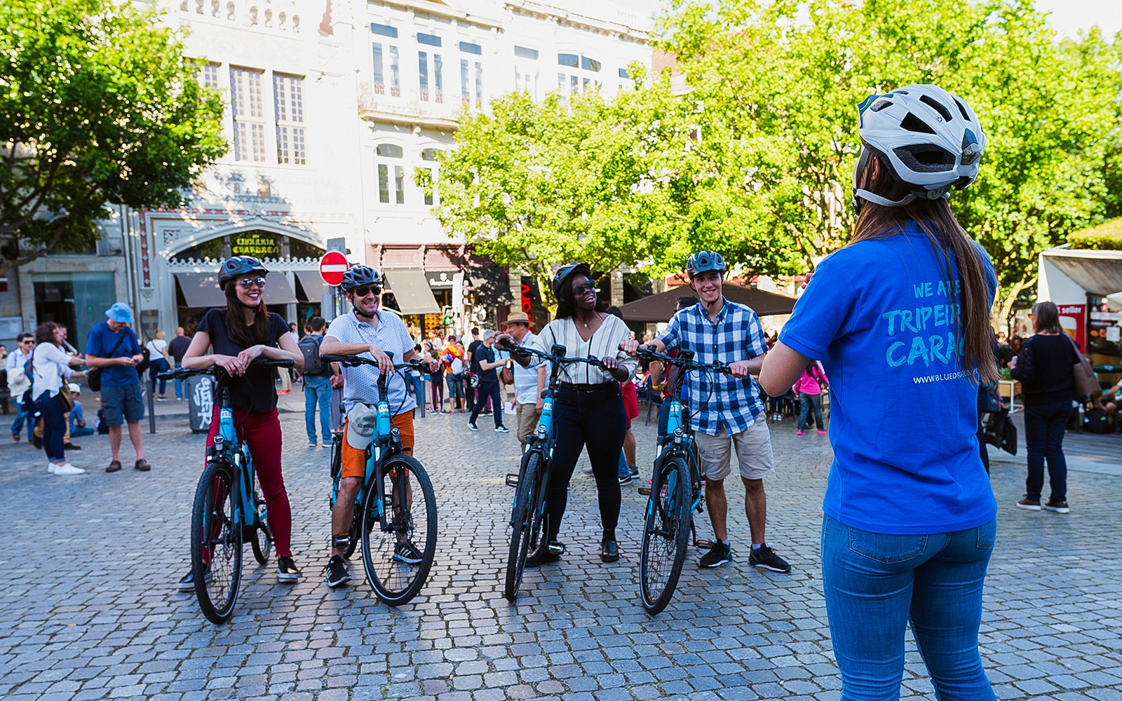 Grupo de ciclistas com um guia na praça da Cidade Velha durante um passeio de bicicleta.