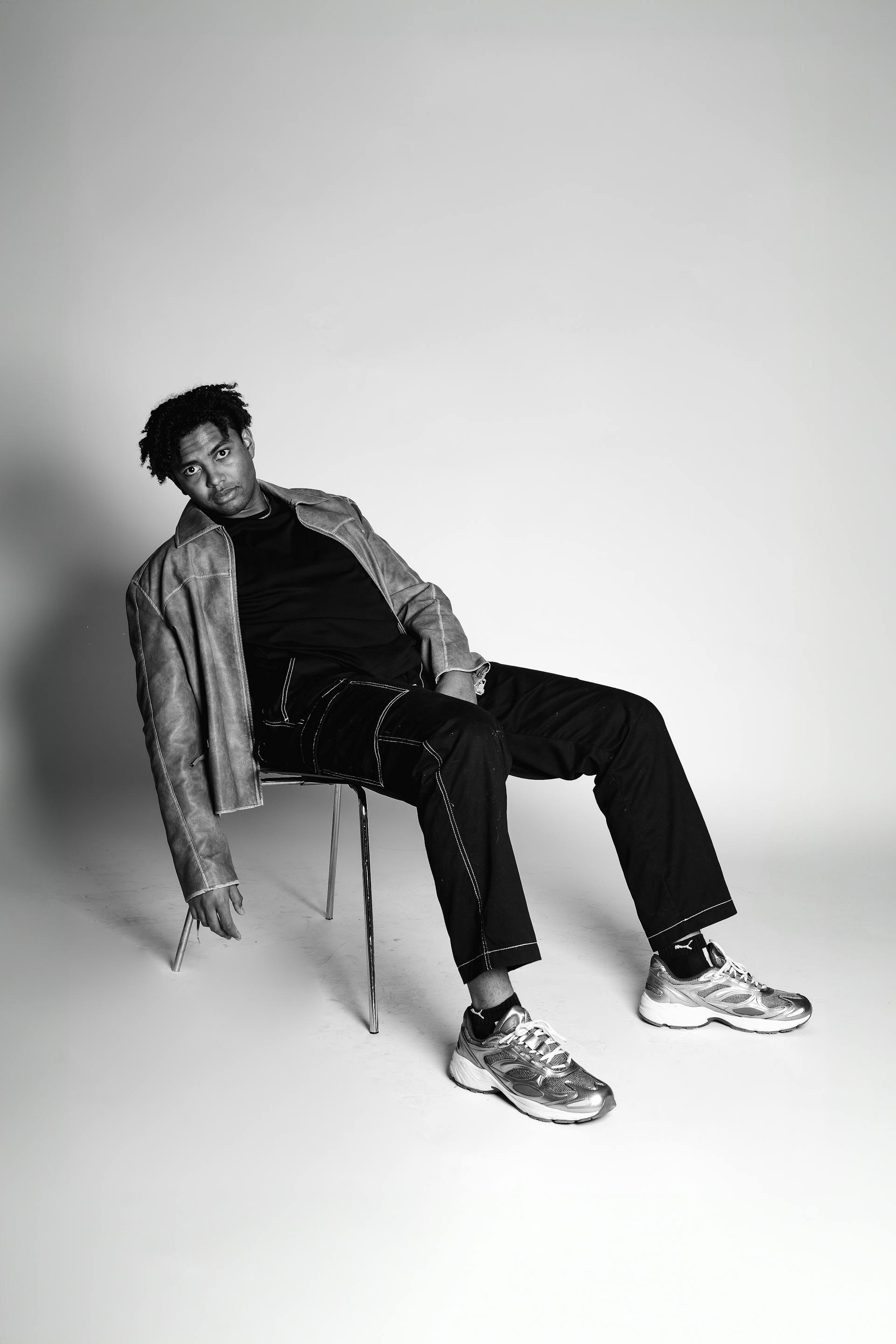 A man seated while pausing dynamically, setead on a small chair