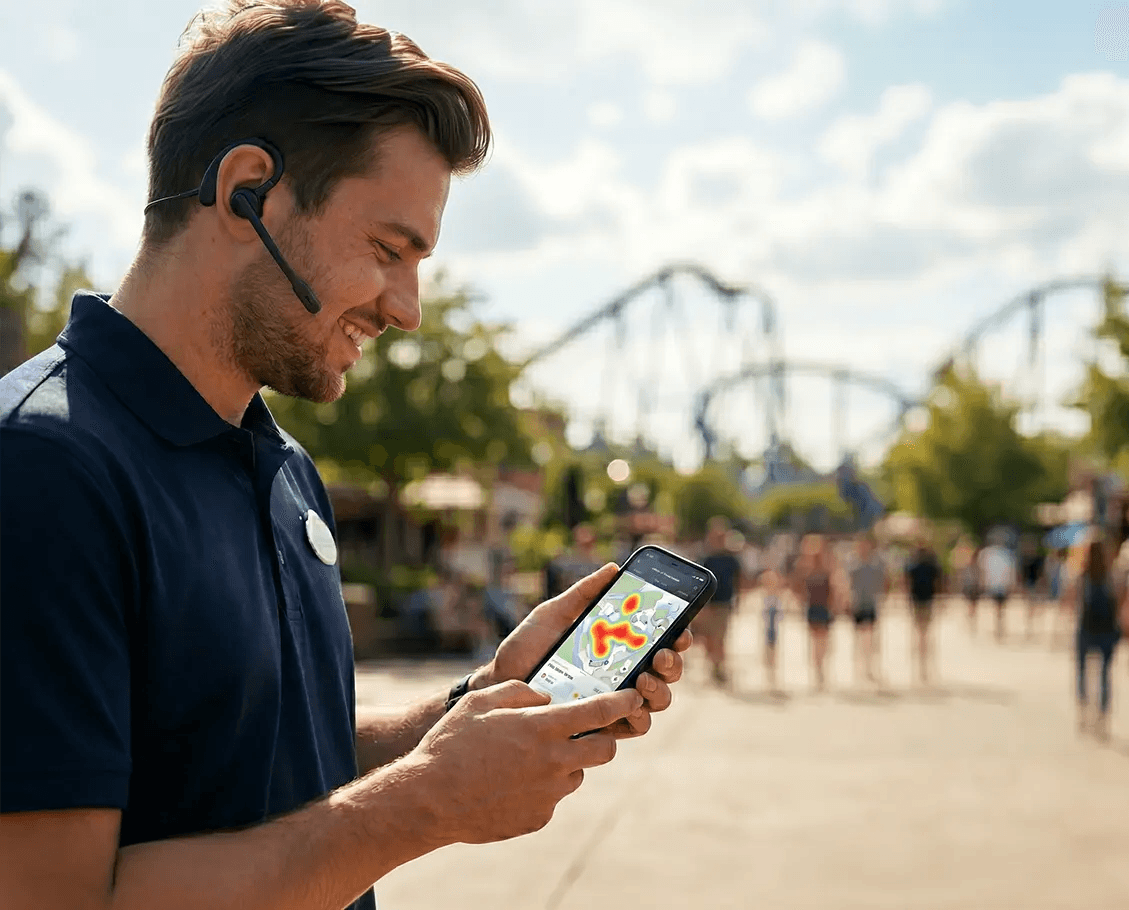 Ein Parkmitarbeiter mit Headset überprüft eine Live-Heatmap des Parks auf einem Smartphone