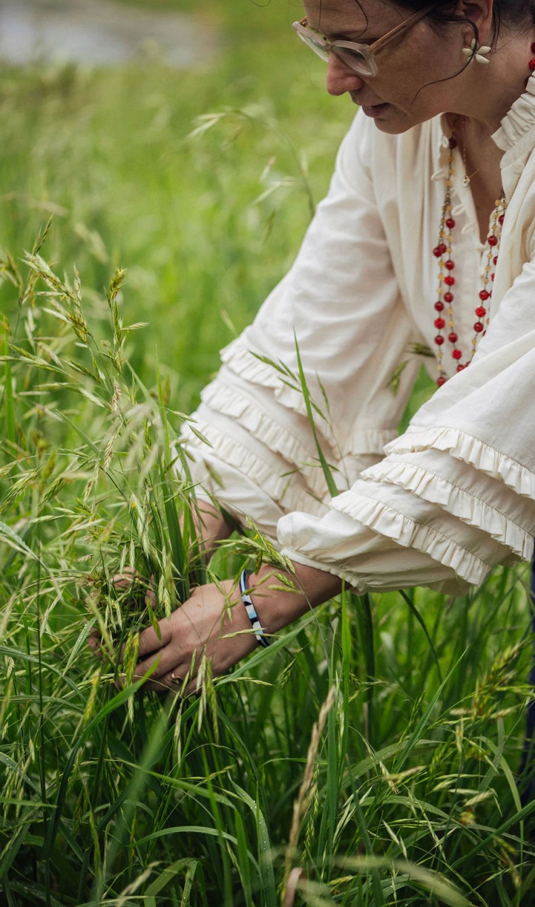 Mujer observando la vegetación entre hierbas altas en un campo.