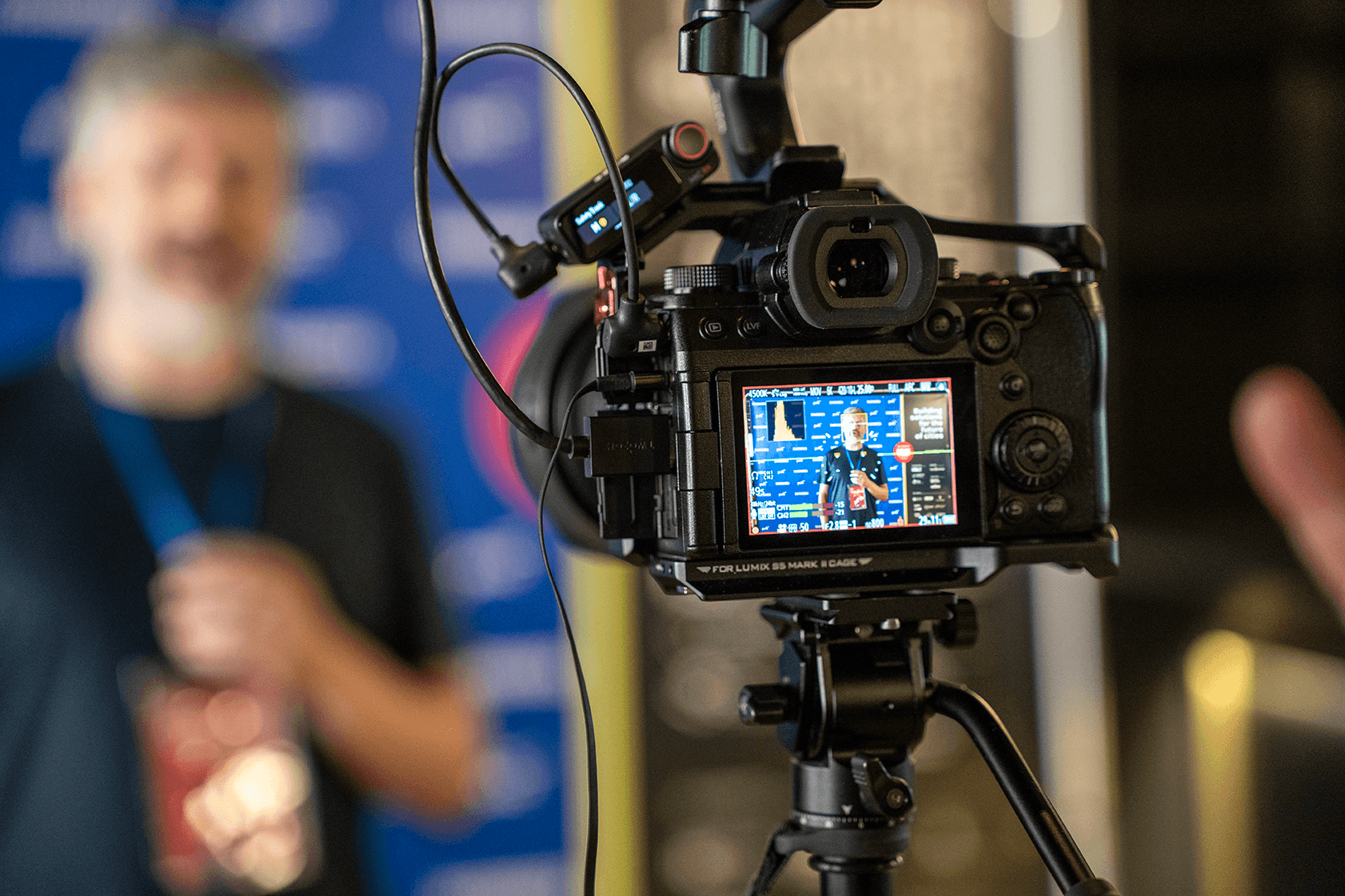 A woman in red lighting holding a tablet while getting filmed.
