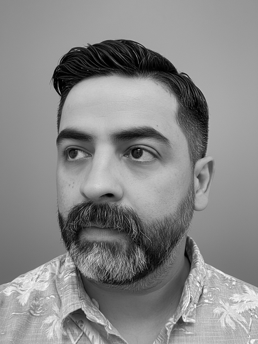 A thoughtful young person with dark hair gazes to the side, captured in soft black and white lighting.