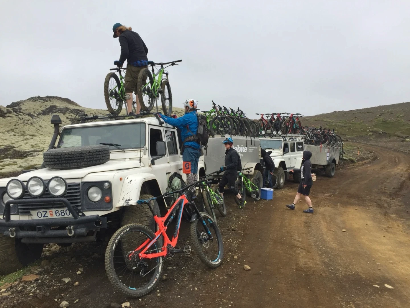 A row of modified superjeeps with bikes being offlodes in Iceland nature