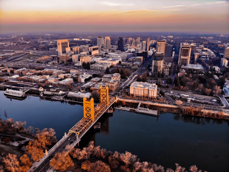 Aerial view of Sacramento, California skyline with Tower Bridge and the Sacramento River at sunset.