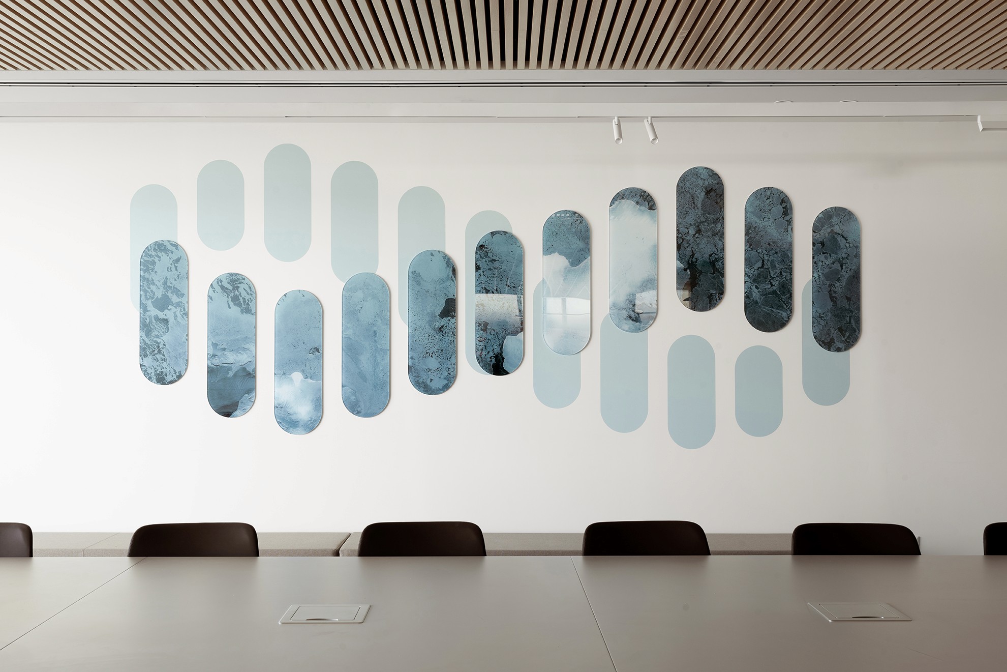 אומנות במשרד: קיר כוח בחדר הישיבות עם יצירת אומנות אבסטרקטית (Blue Ovals) בגווני המותג, המוסיפה עומק וצבע לחלל.