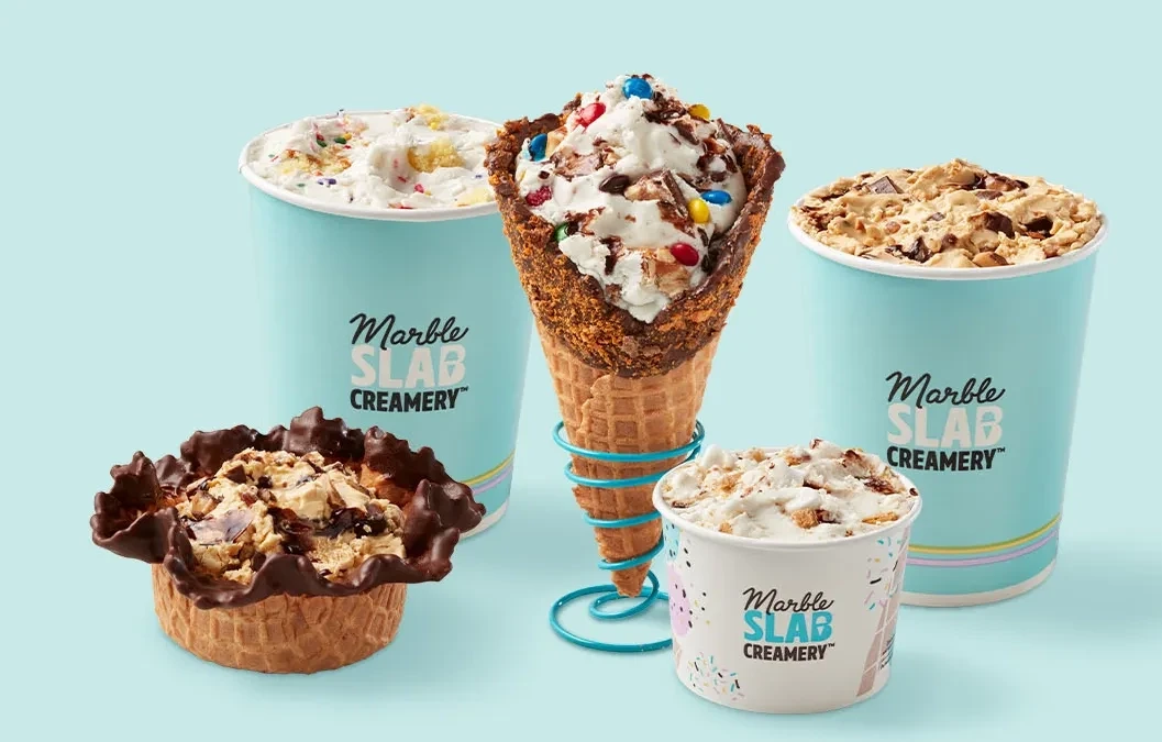 Marble Slab Creamery ice cream in waffle cones, a chocolate-dipped waffle bowl, and cups topped with candy and cookie mix-ins
