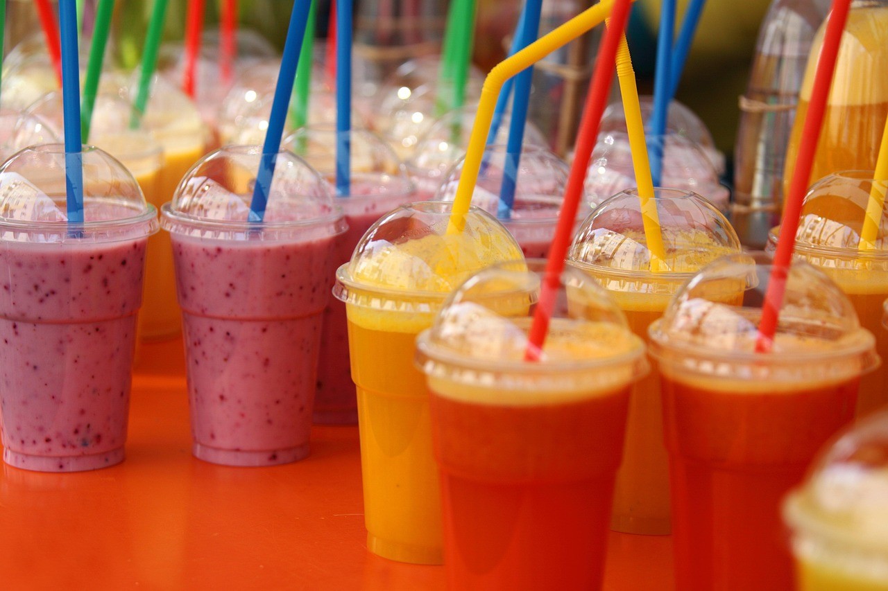 Colorful smoothies assortment with straws - berry, mango, and other flavors.