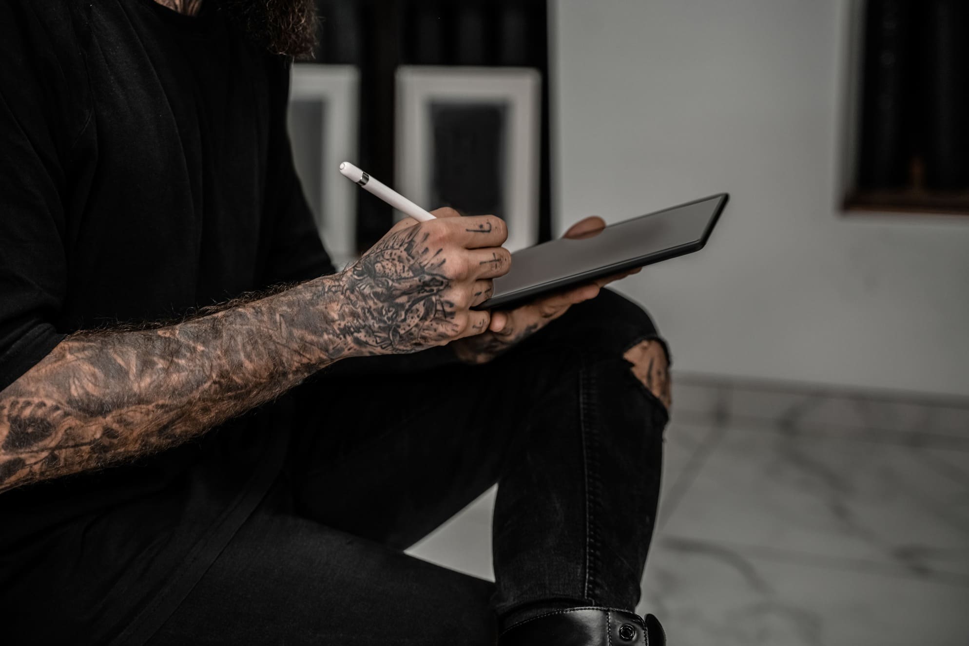 Tattooed artist using a tablet and stylus while seated