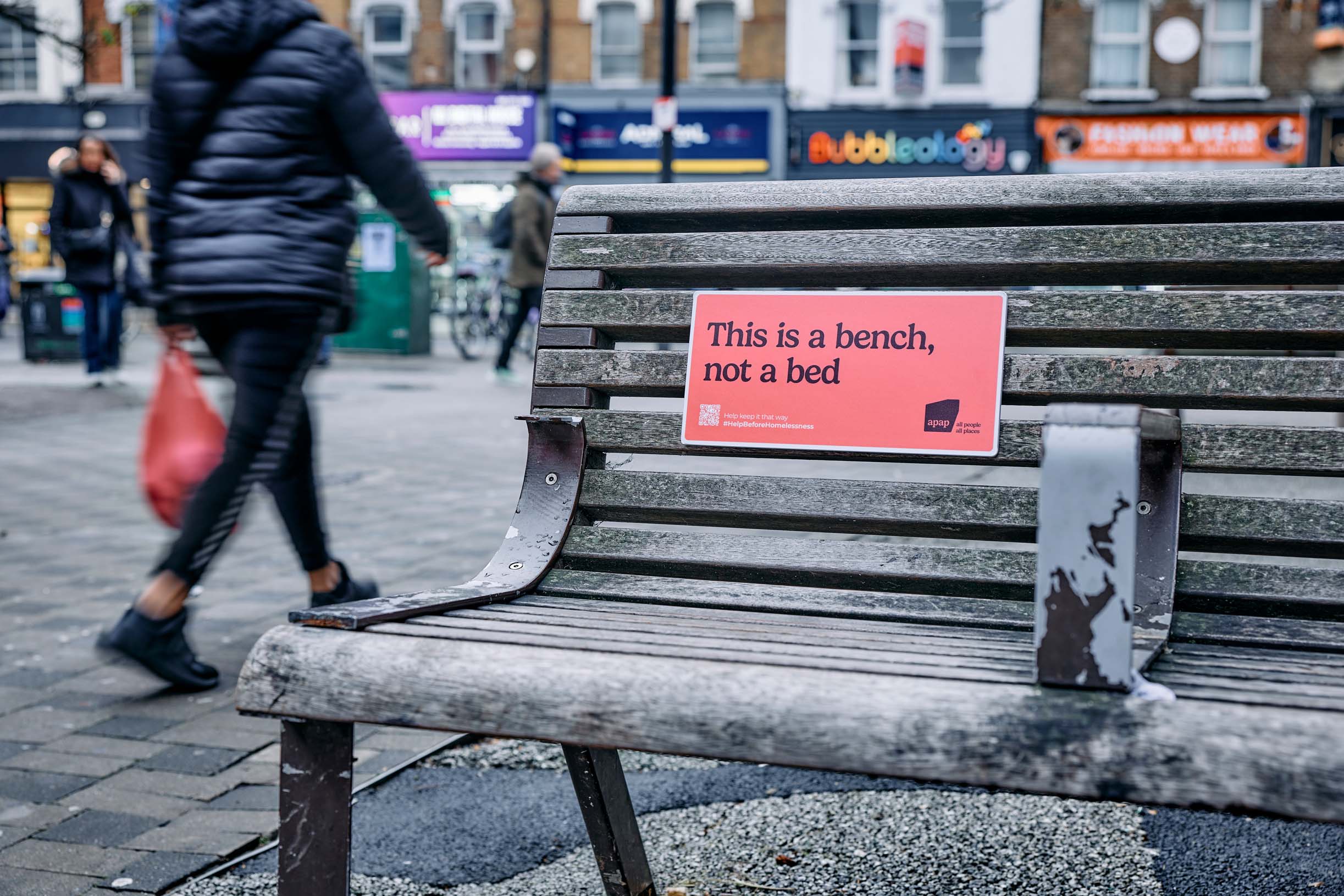 A sign on a bench that reads 'This is a bench not a bed'