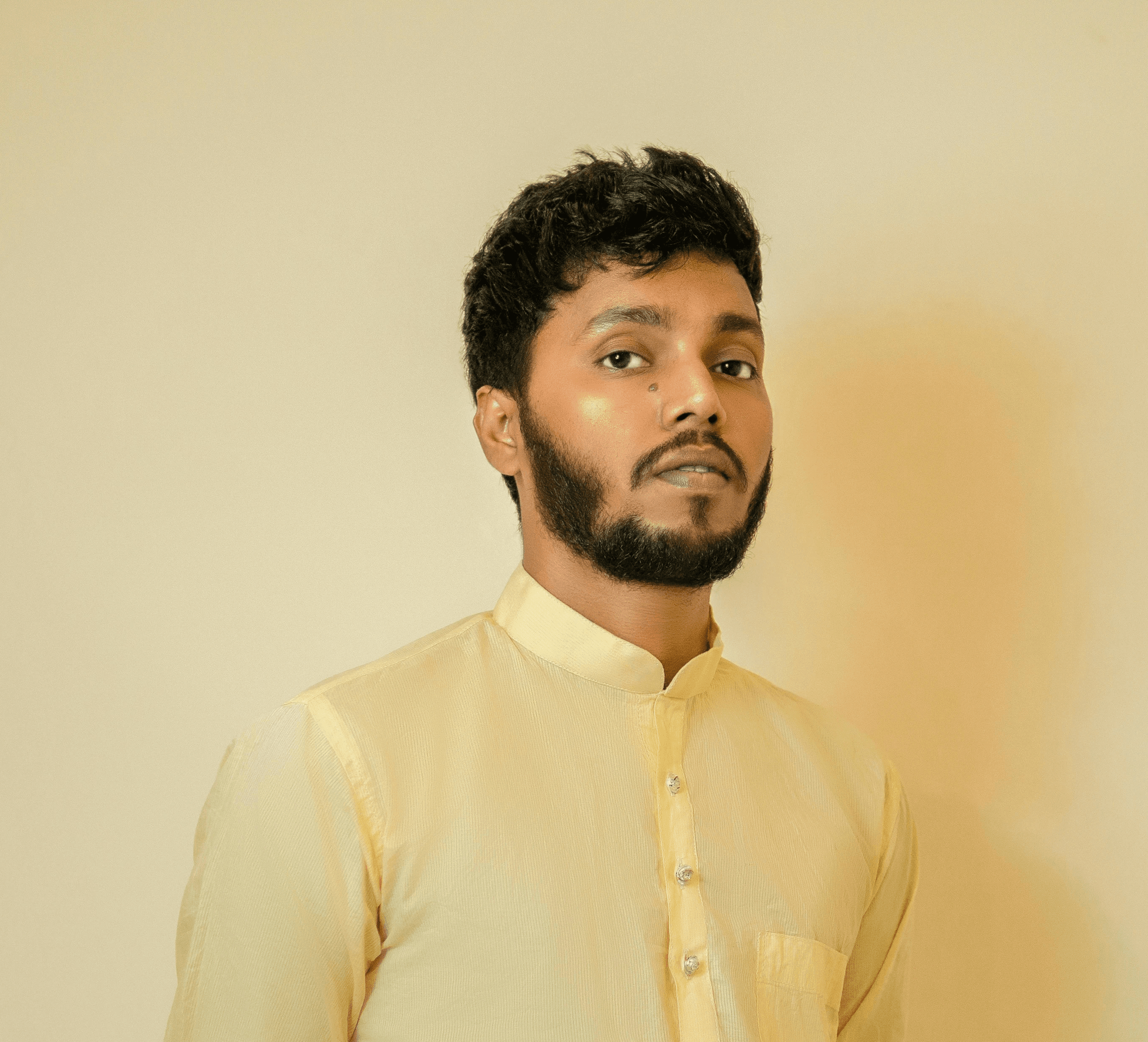a man standing in front of a wall wearing a yellow shirt