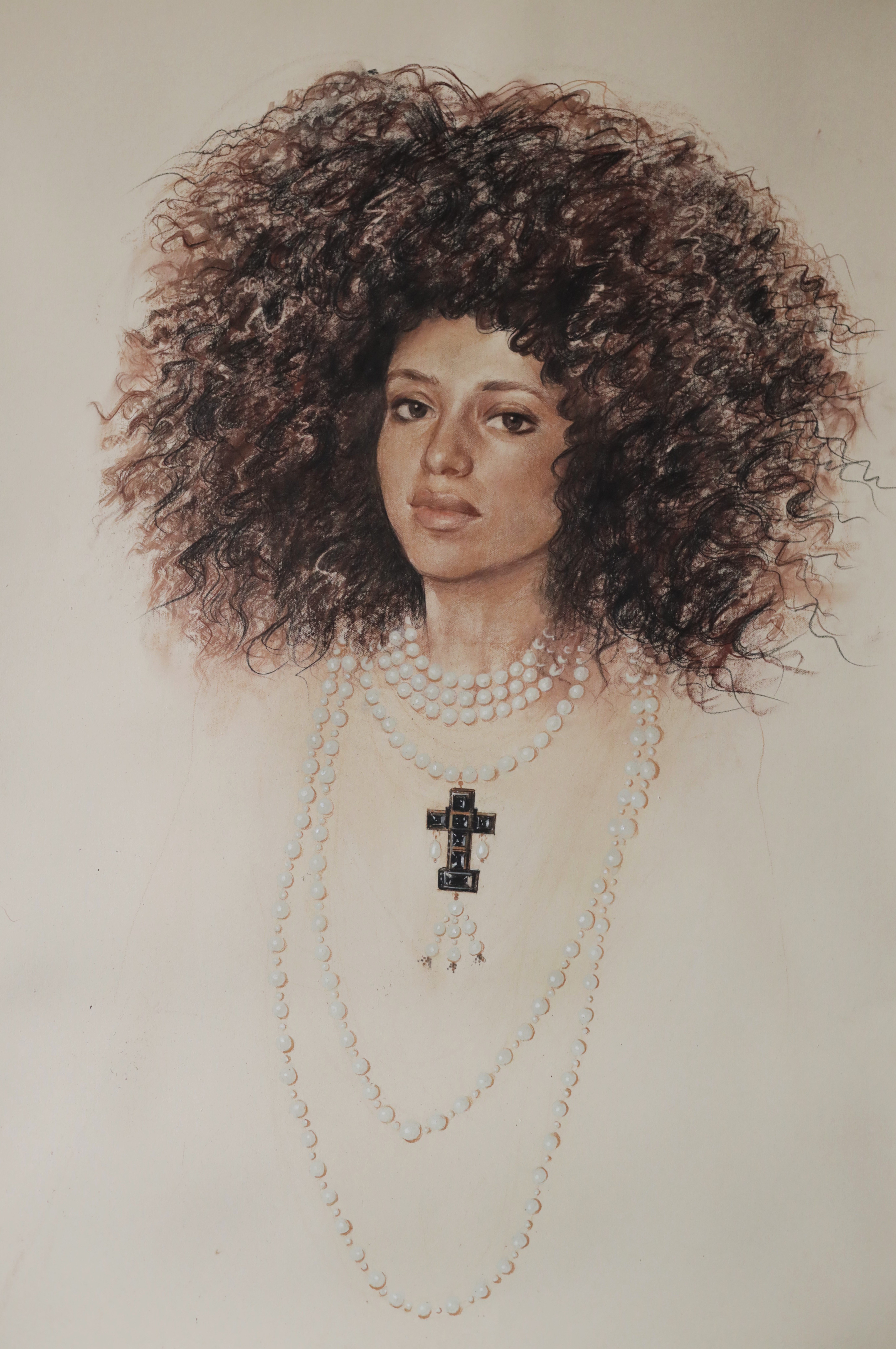 A portrait of a person with voluminous curly hair, wearing layered pearl necklaces and a prominent cross pendant, set against a neutral background.
