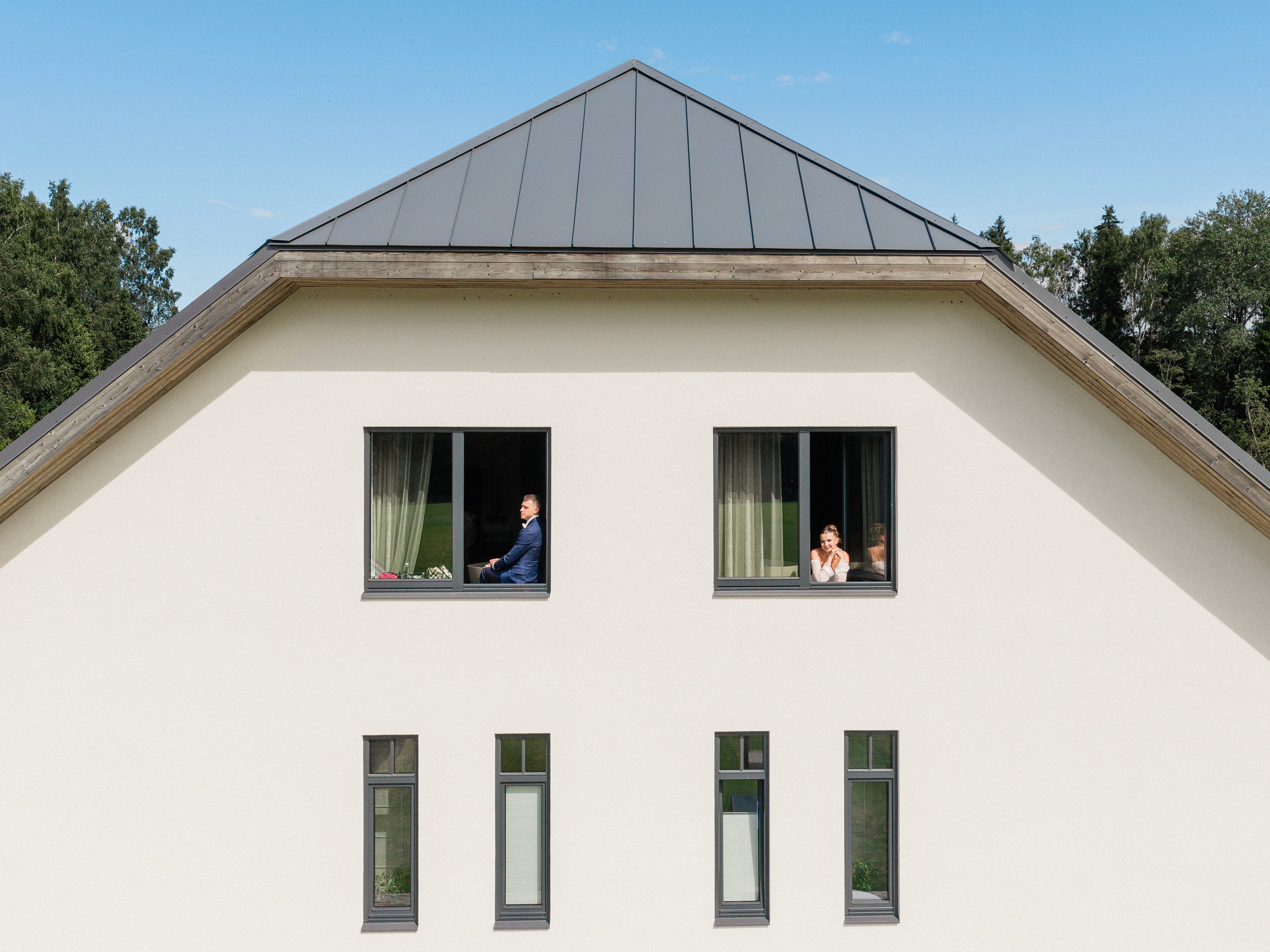 Symmetrical pale venue façade with two people visible in upper windows.