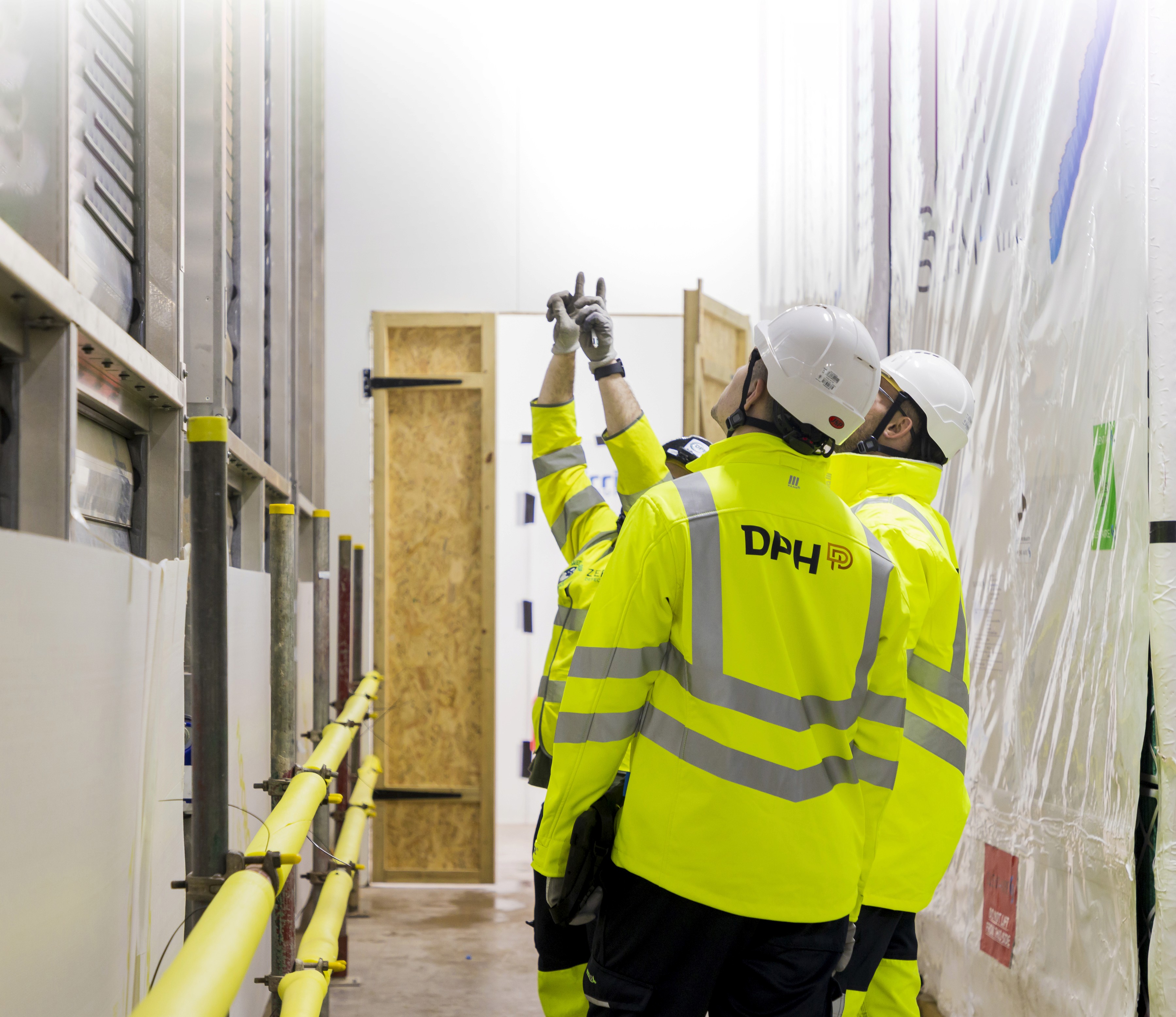 Modern glass building with illuminated interior and reflections at sunset