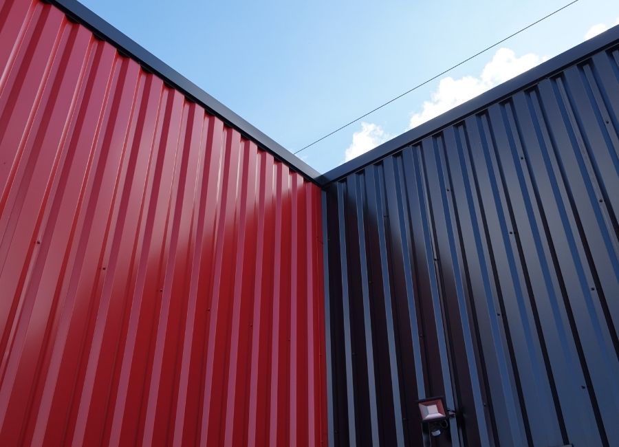 Jonction de bardage métallique rouge et noir sur une structure industrielle.