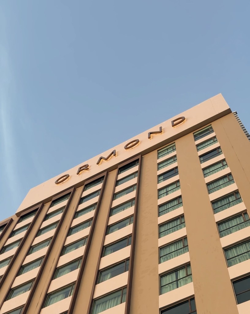 A low angle view of a tall building with the name 'ORMOND' prominently displayed at the top against a clear blue sky.