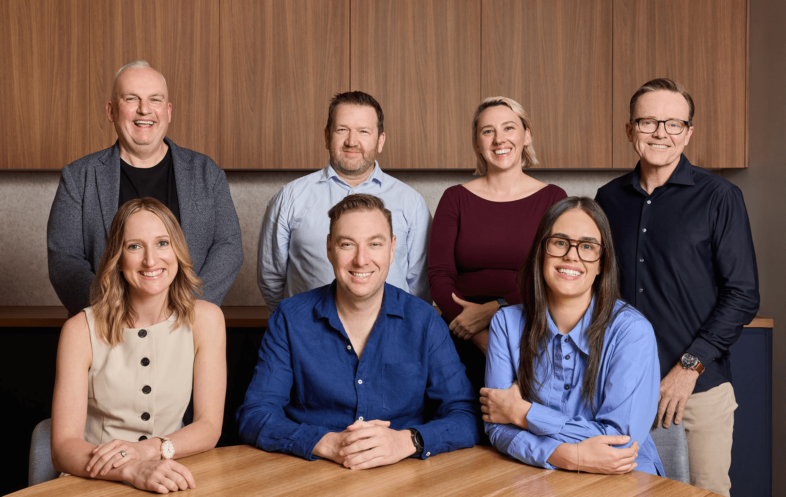 Silhouetted figures walking through a modern building hallway with glass windows and blinds reflecting light.