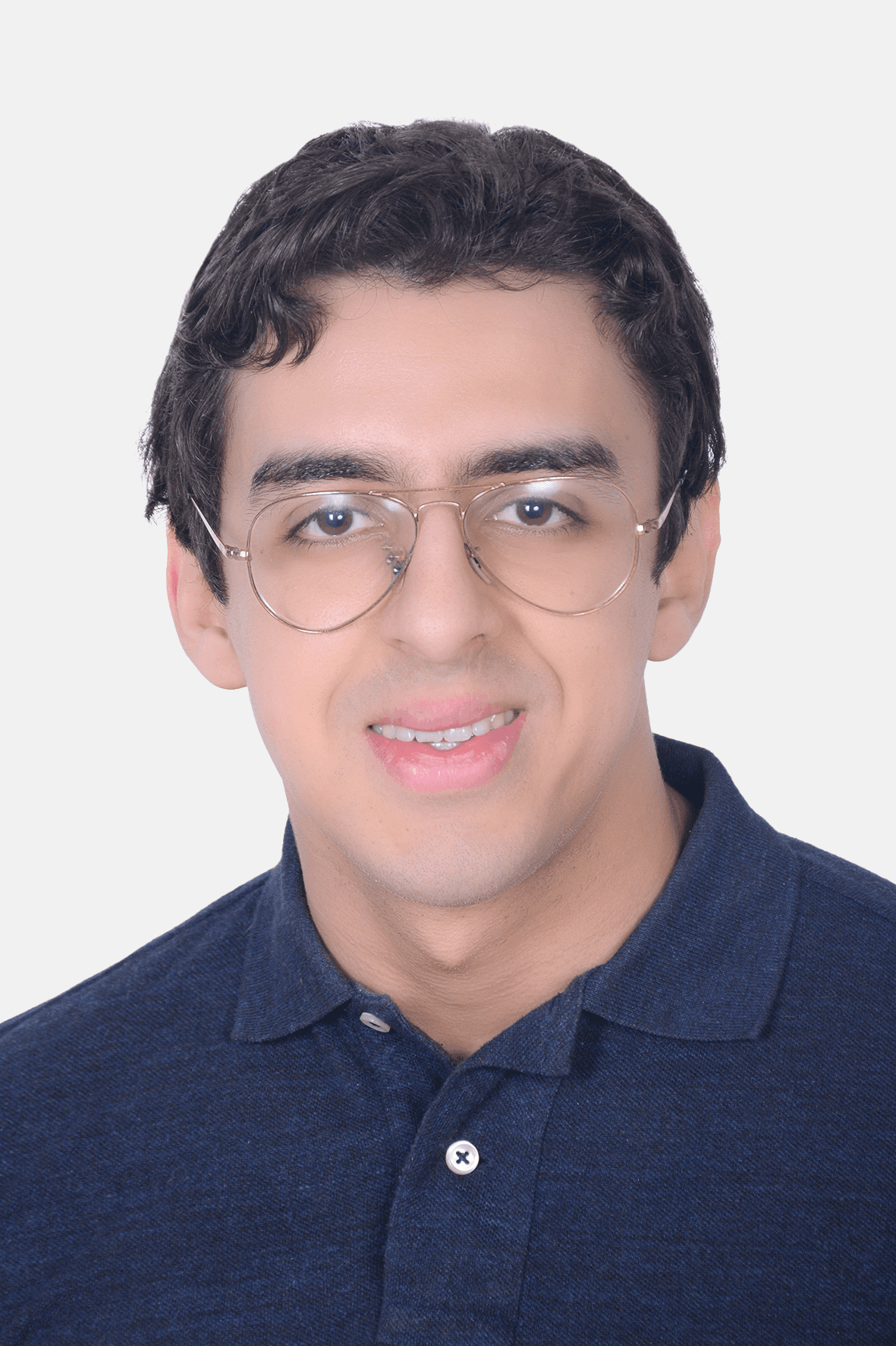 A person wearing headphones sits at a desk with a large curved monitor displaying graphic design software, surrounded by a laptop, smartphone, and potted plant, creating a modern workspace setup.