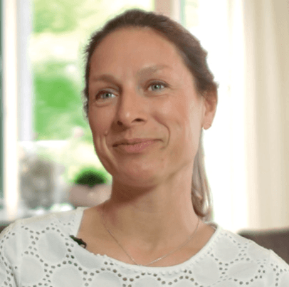 Porträt einer lächelnden Frau mittleren Alters mit braunen Haaren und dezenter Kleidung.